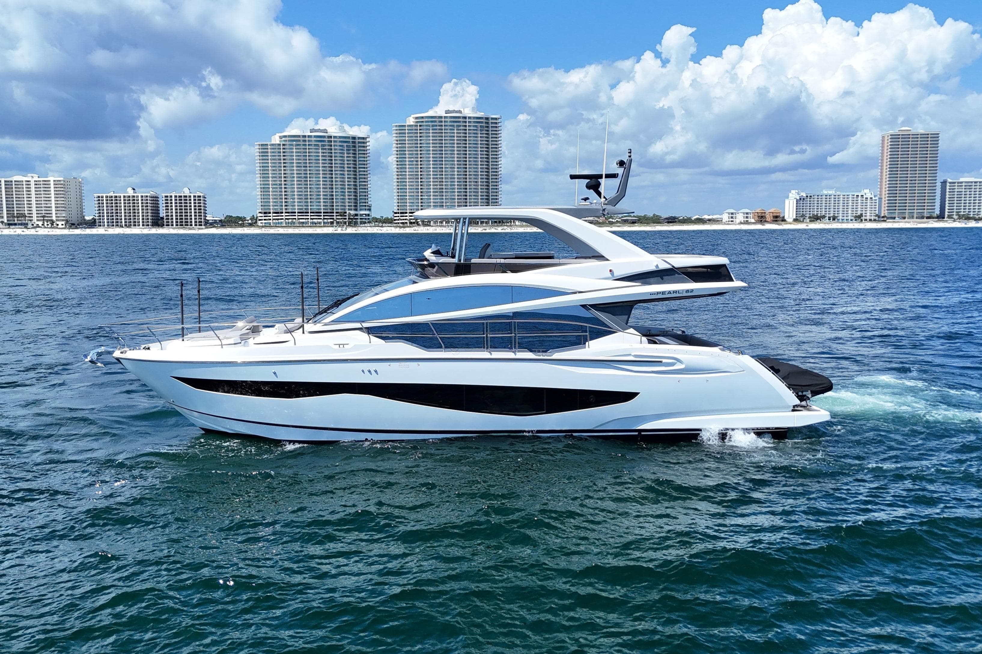 Luxury Pearl 62 yacht cruising on ocean, 2022 model, with city skyline in background.