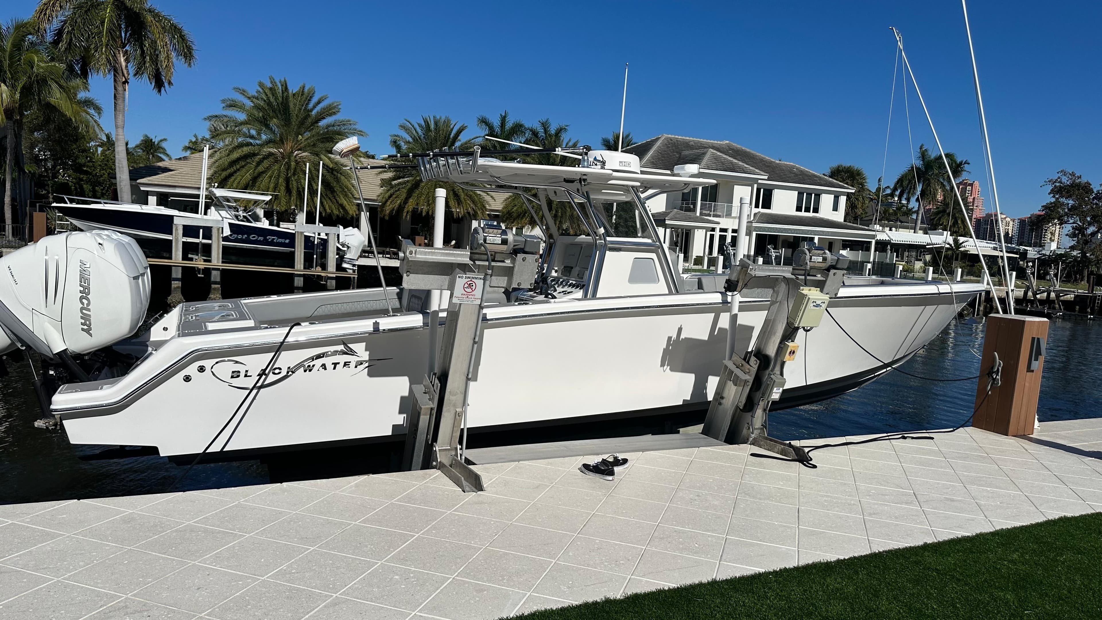 2021 Blackwater 36 SF boat docked by waterfront homes, surrounded by palm trees.