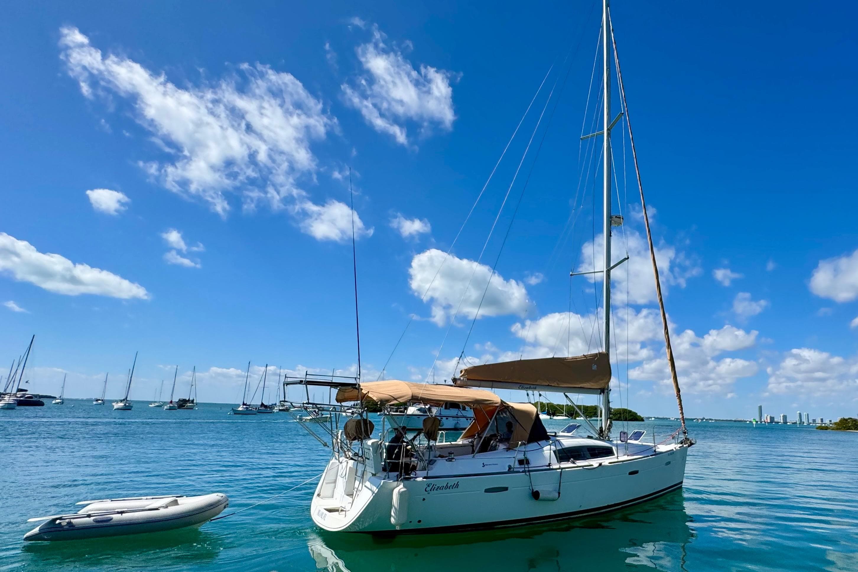 2008 Beneteau Oceanis 40 sailboat anchored in a sunny bay with clear skies.