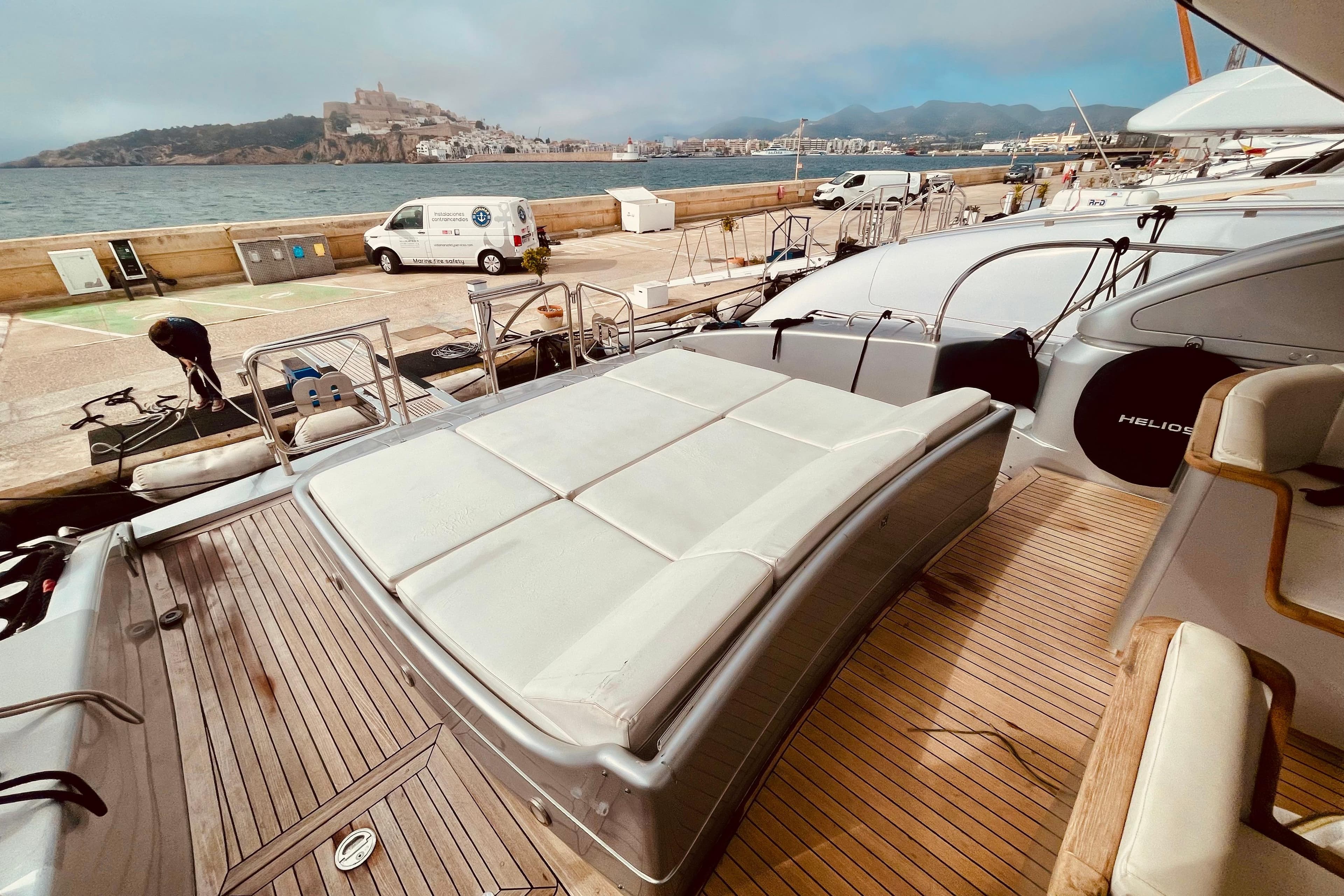 Luxurious 1999 Mangusta 72 yacht docked with scenic coastal view.