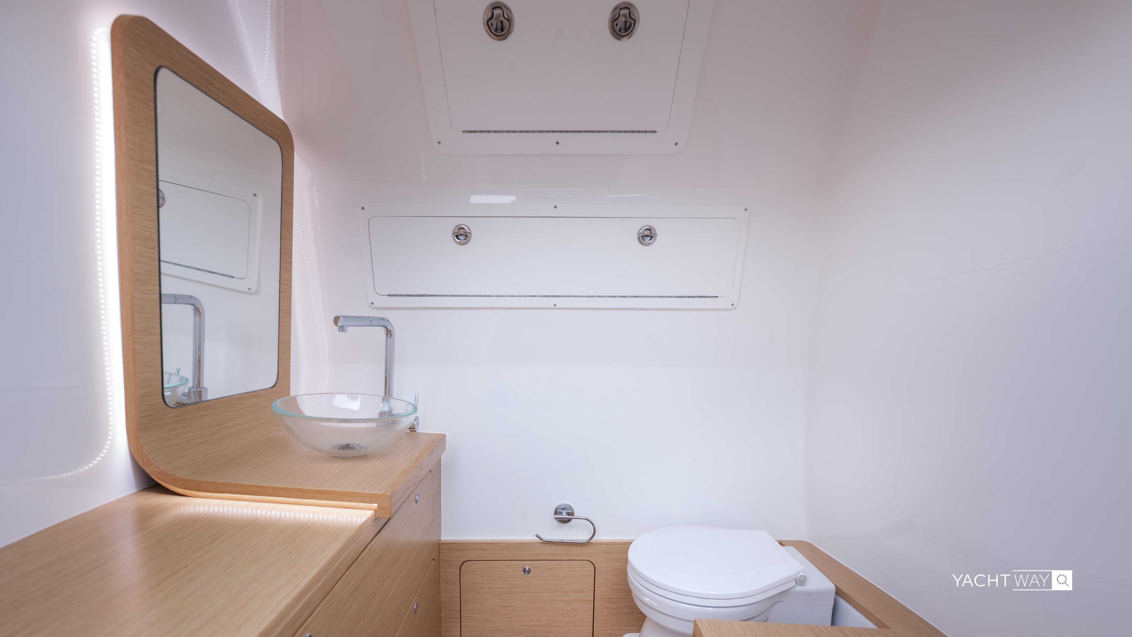 Modern yacht bathroom with wooden vanity, glass sink, and toilet on Skipper-BSK 38NC, 2025 model.