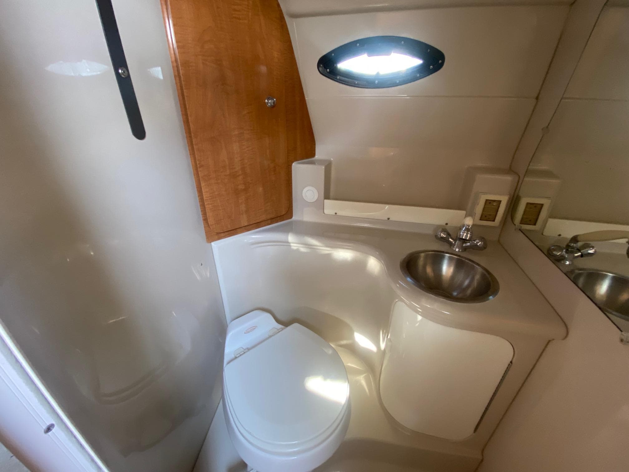 2004 Regal 2665 Commodore boat bathroom with toilet, sink, and wooden cabinet.
