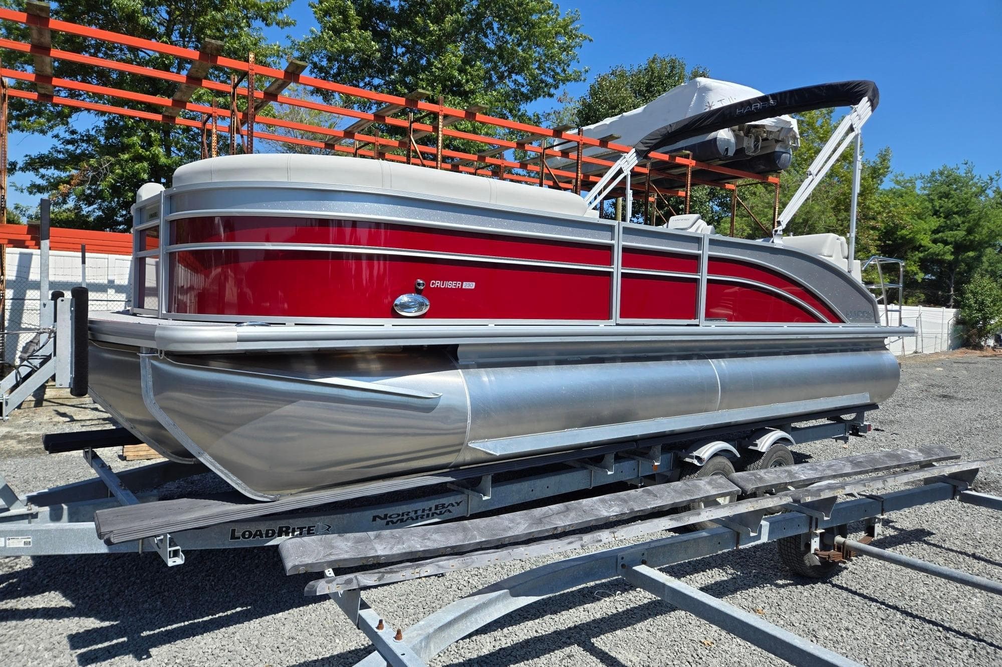 2026 Harris Cruiser 230 pontoon boat with red and silver design on a trailer.