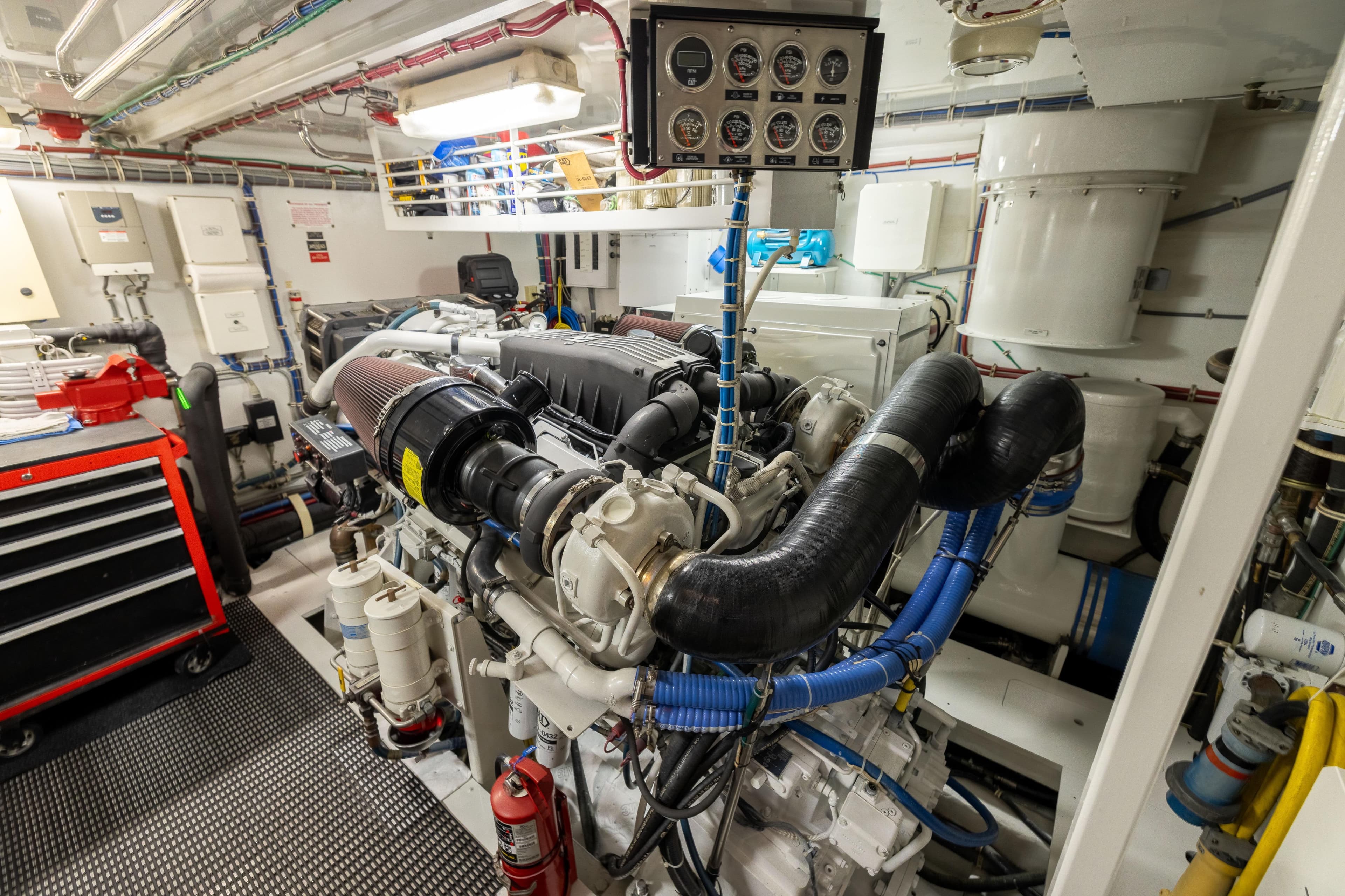 Engine room of 2005 Hatteras 80 Motor Yacht, featuring complex machinery and control panel.