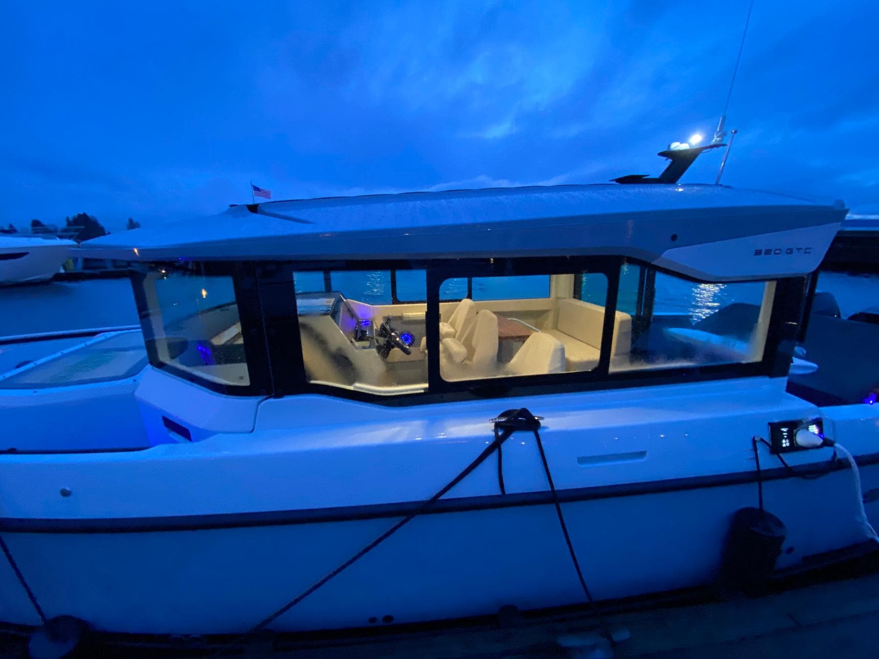 2025 Saxdor 320 GTC boat docked at twilight, illuminated interior, sleek design.