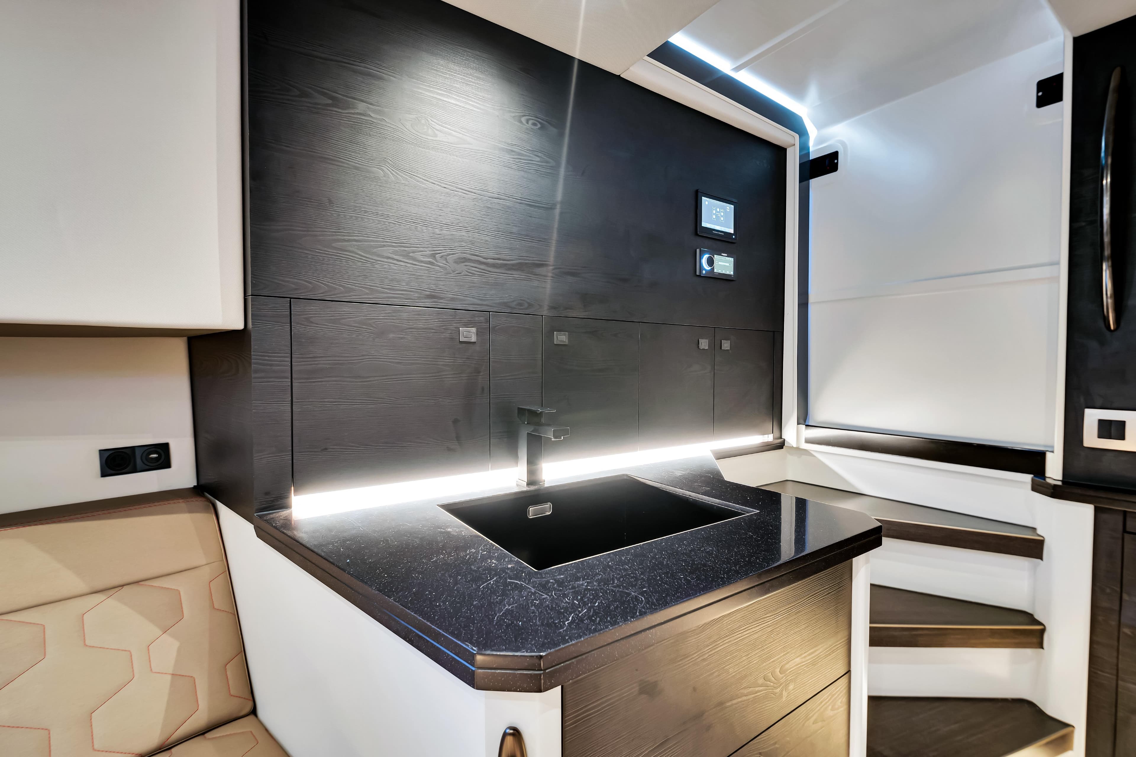 Modern interior of 2021 Vanquish Yachts 45 with sleek black sink and ambient lighting.