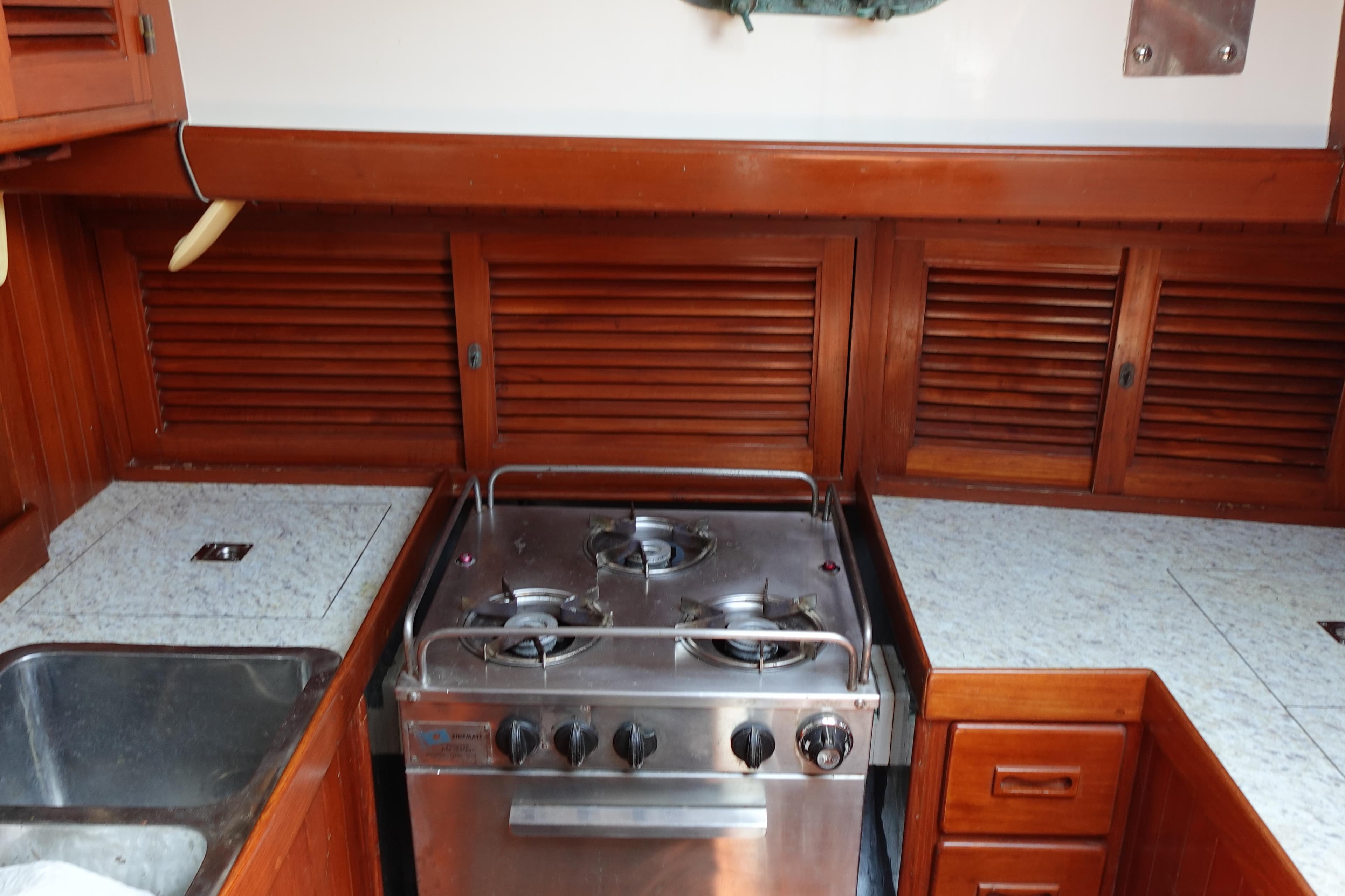 Galley kitchen in 1985 Tayana 37 Cutter sailboat with stove and wooden cabinetry.