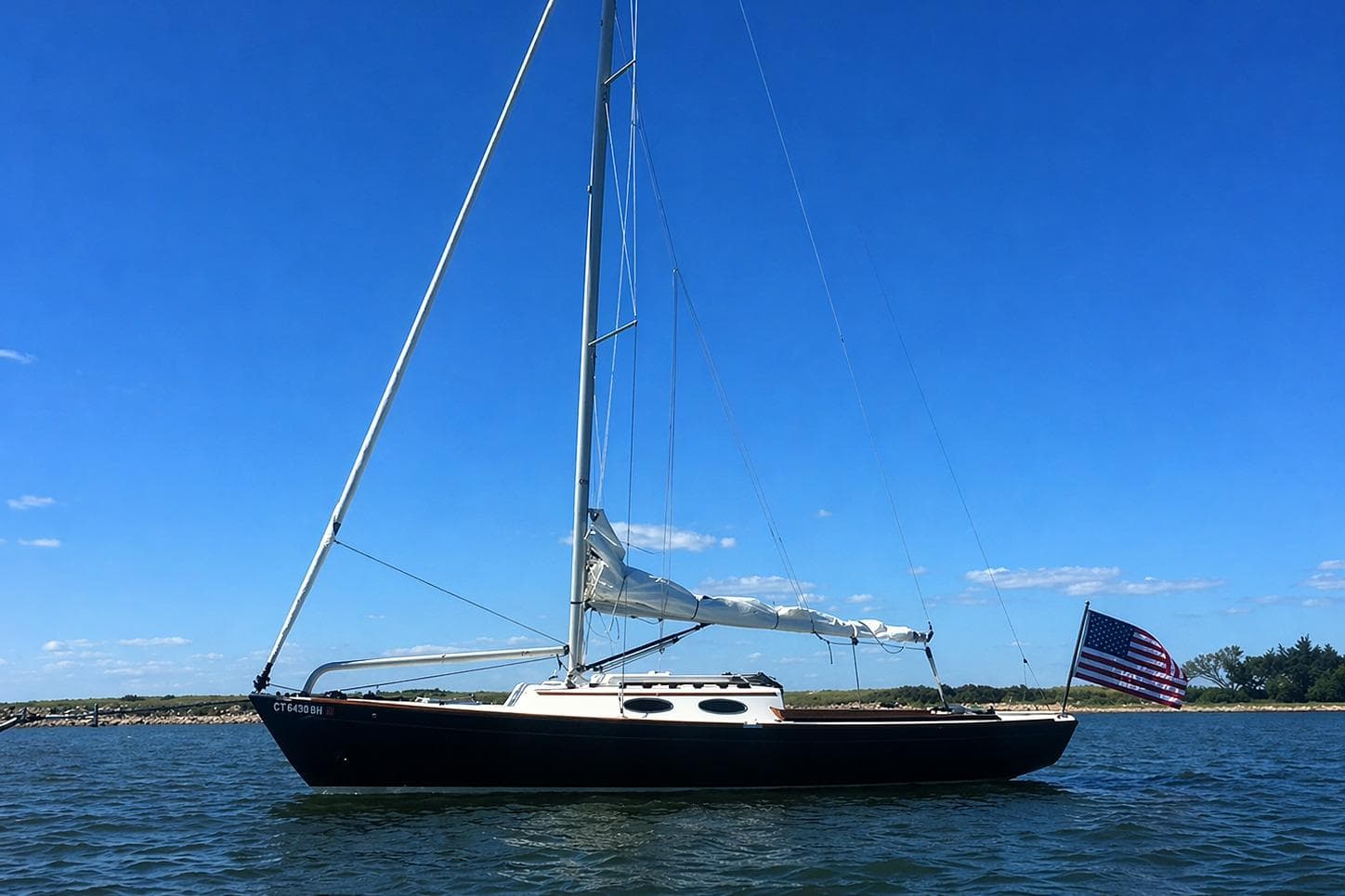 Sailboat Alerion Express 28, 2011 model, on calm water under clear blue sky.