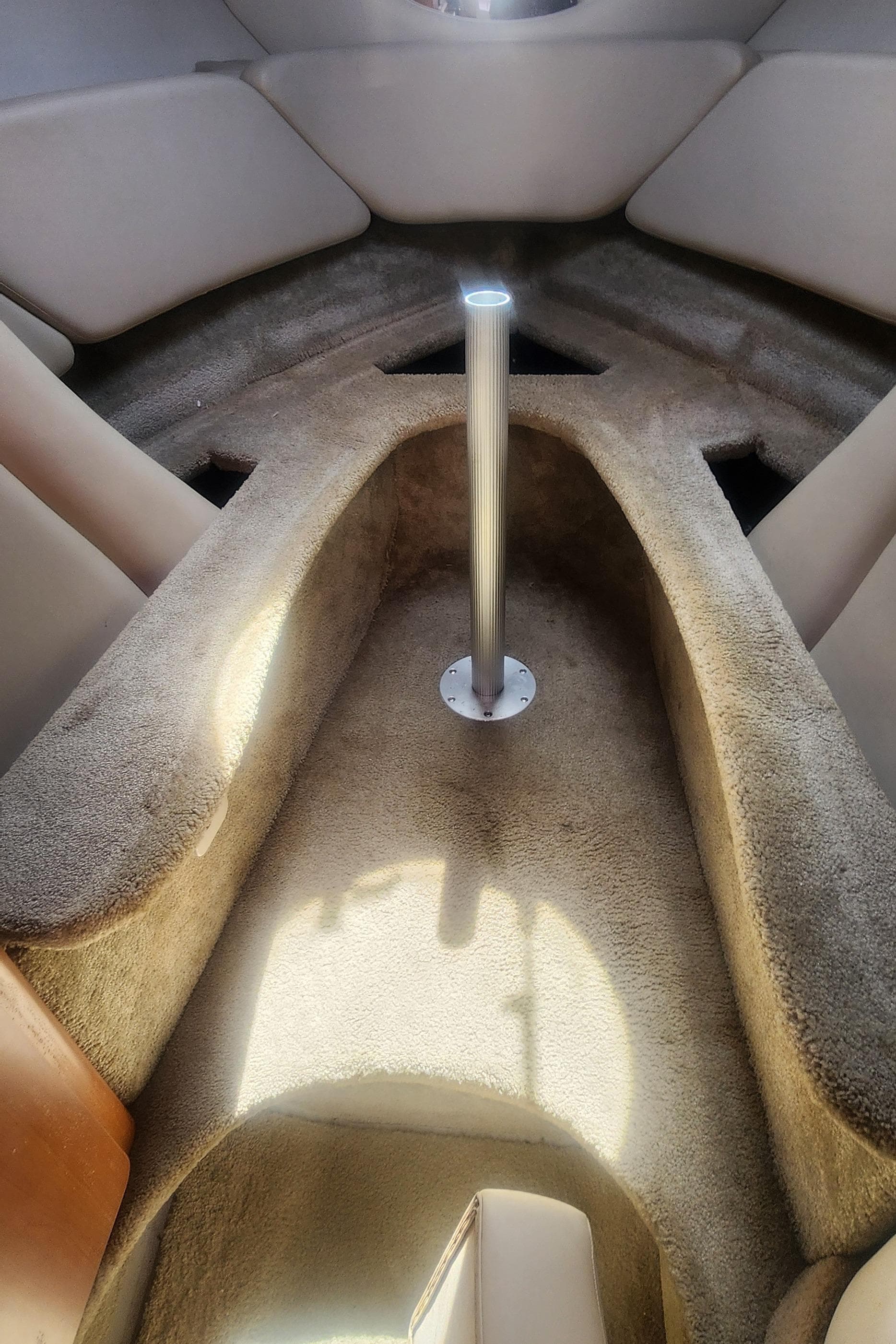 Interior cabin of a 2009 Crownline 250cr boat, featuring plush seating and a central pole.
