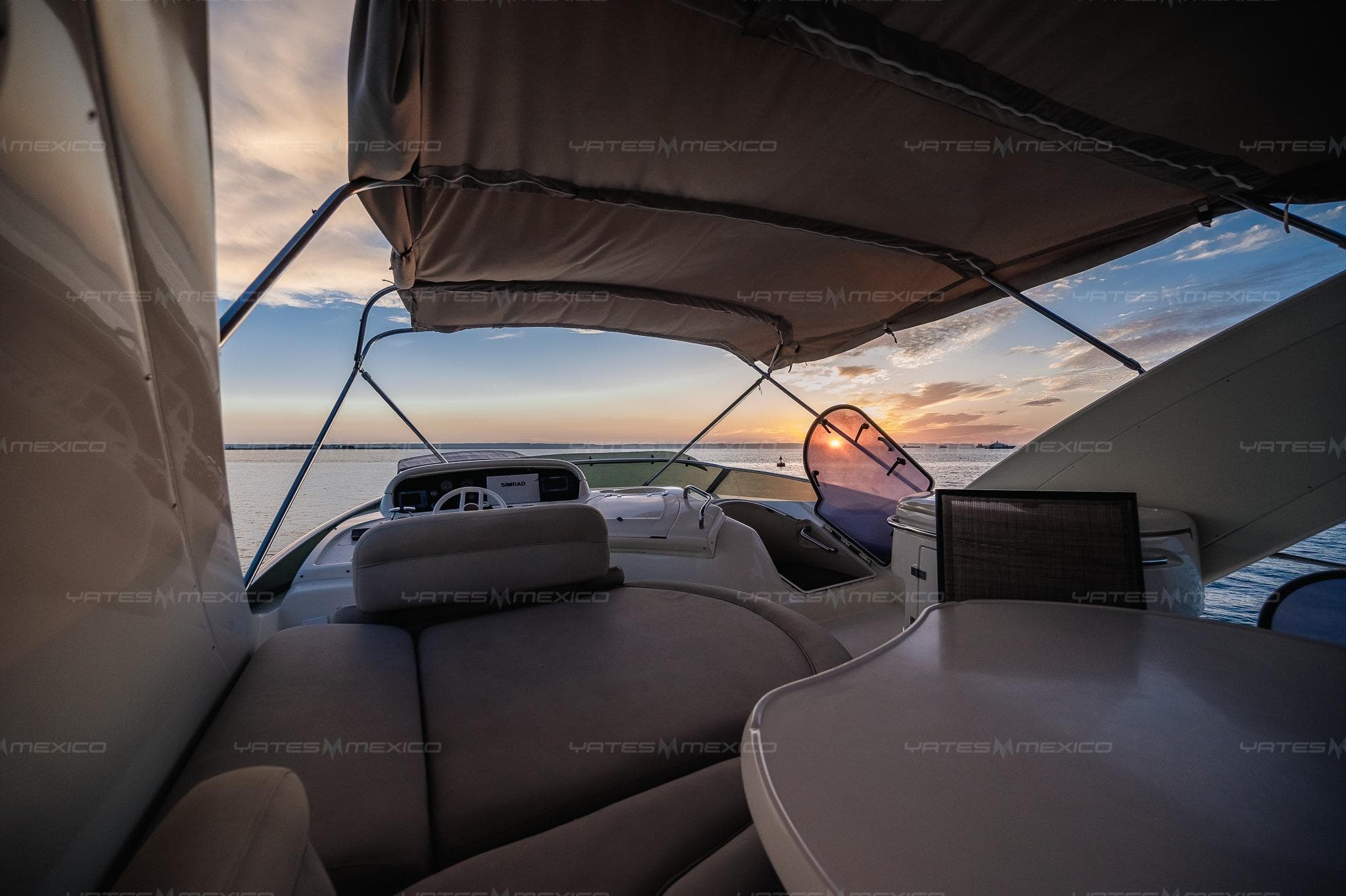 Luxurious 2004 Azimut 68 Plus yacht interior at sunset, featuring elegant seating and ocean views.