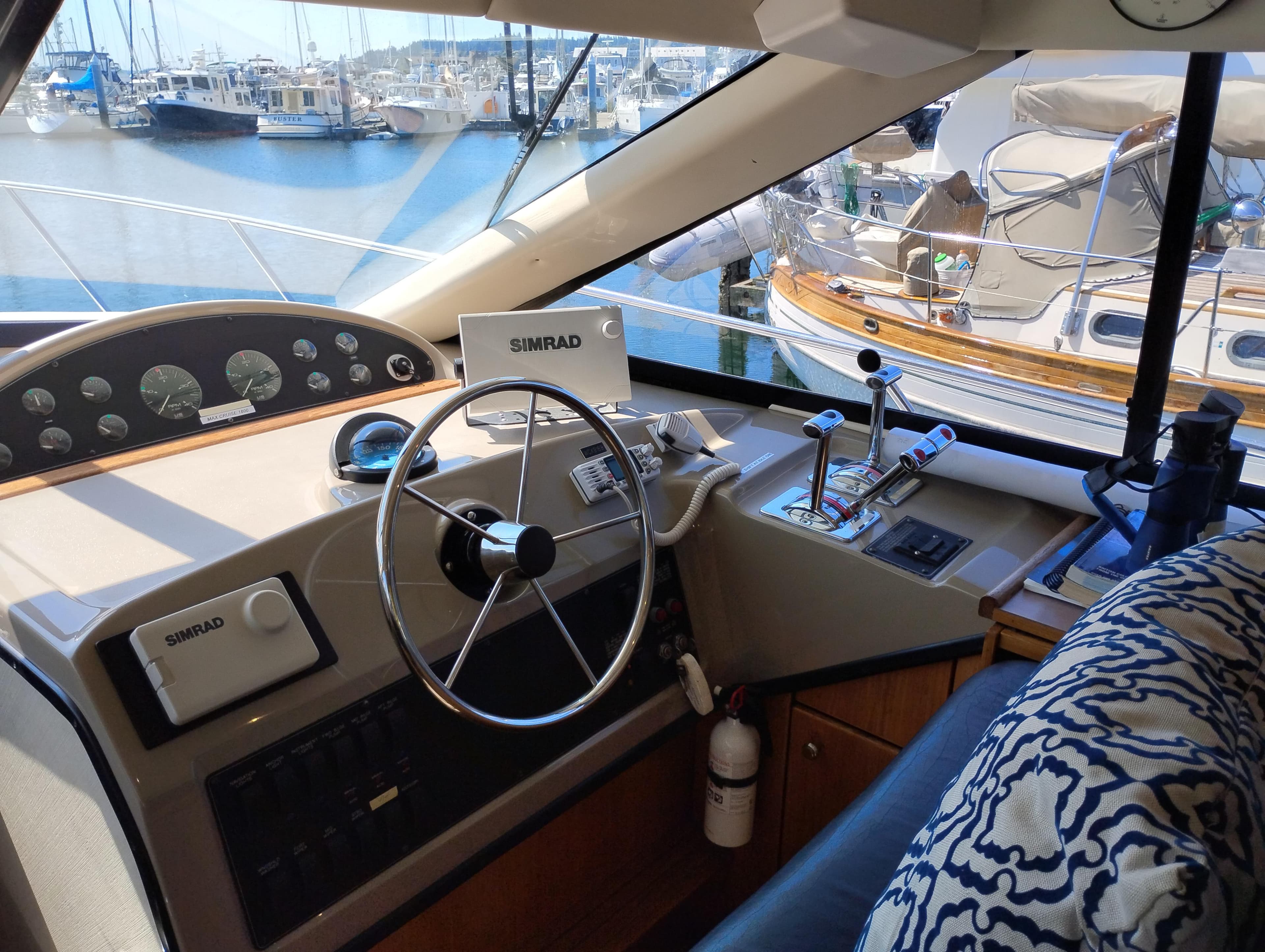 1997 Bayliner 3988 Motor Yacht helm with steering wheel, controls, and marina view.