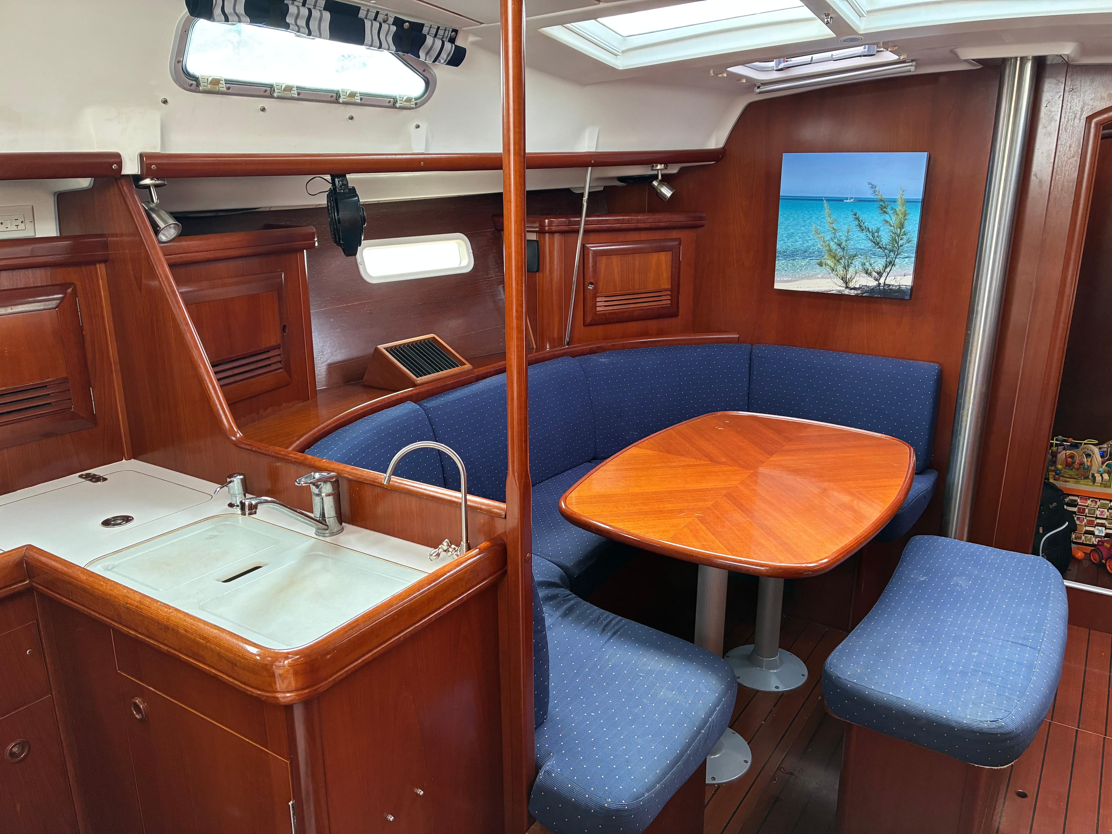 Interior of 2003 Beneteau Oceanis Clipper 393 yacht with wooden dining area and kitchenette.