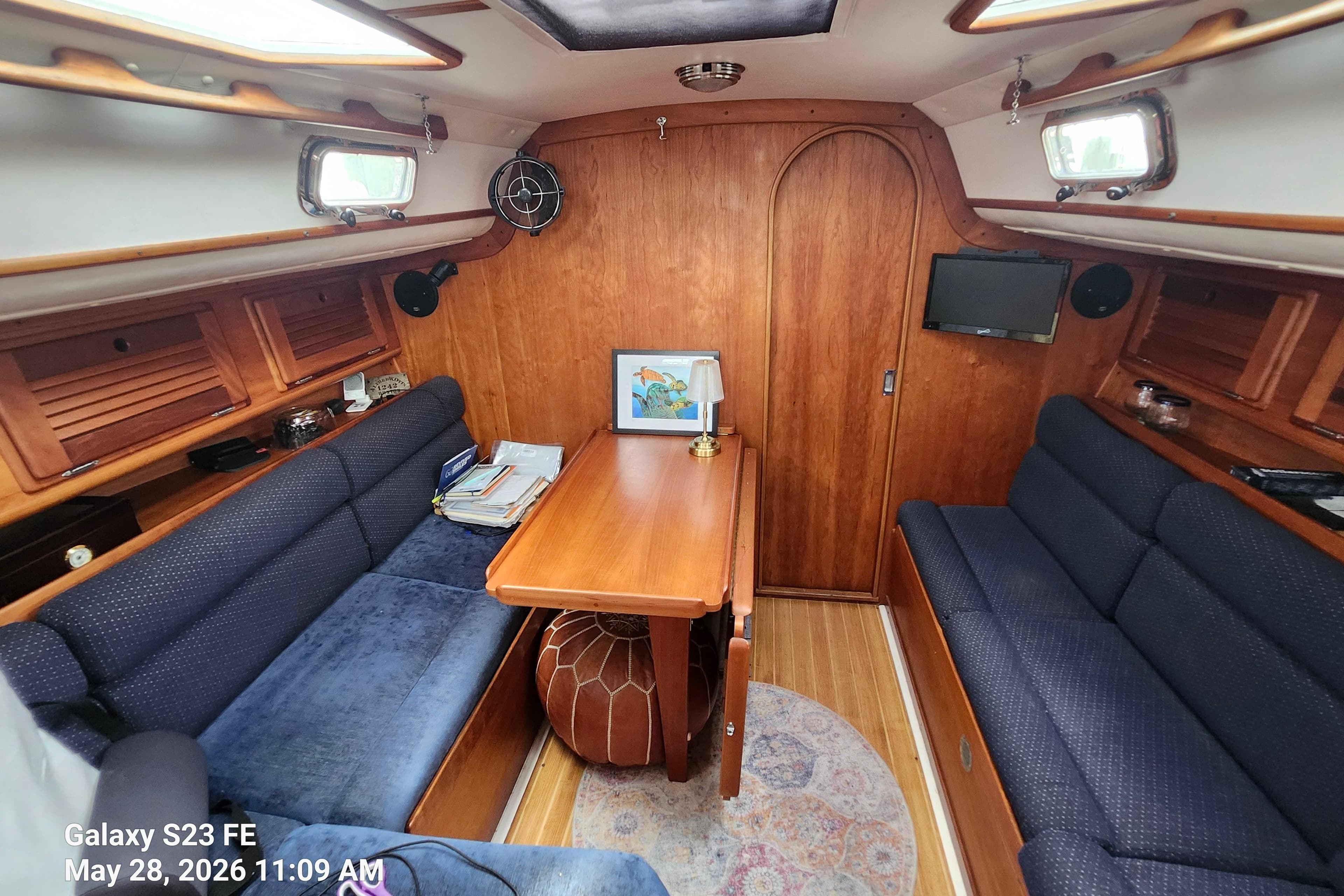 Cozy interior of a 1995 Freedom 35 sailboat with wooden furnishings and blue seating.