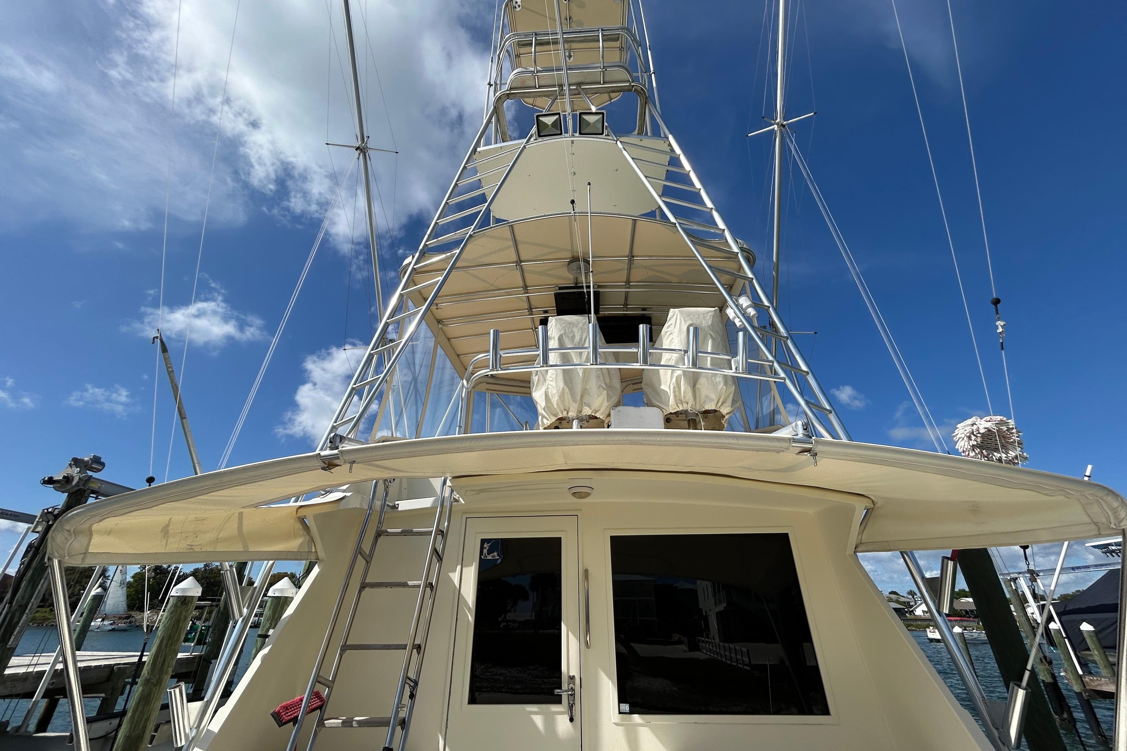1989 Hatteras 45 Convertible yacht with tower, docked under clear blue sky.