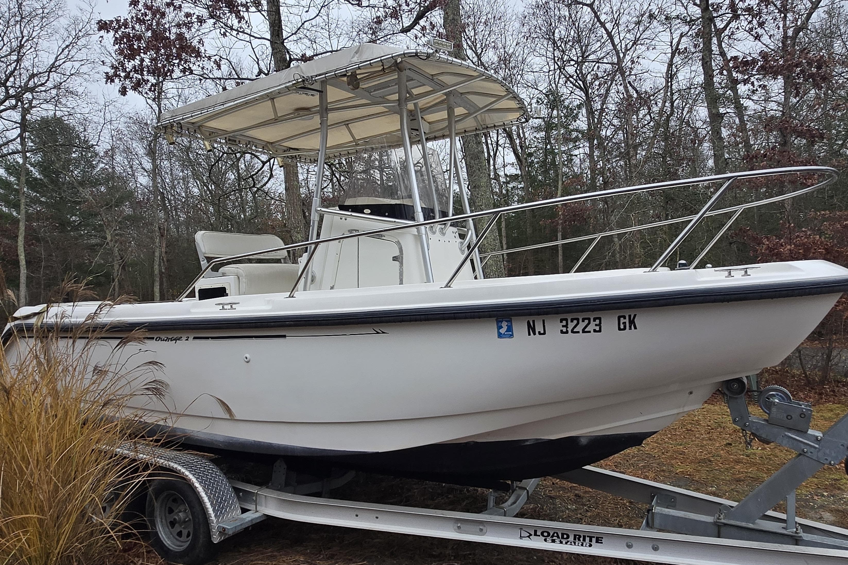 1999 Boston Whaler 21 Outrage boat on trailer in wooded area.