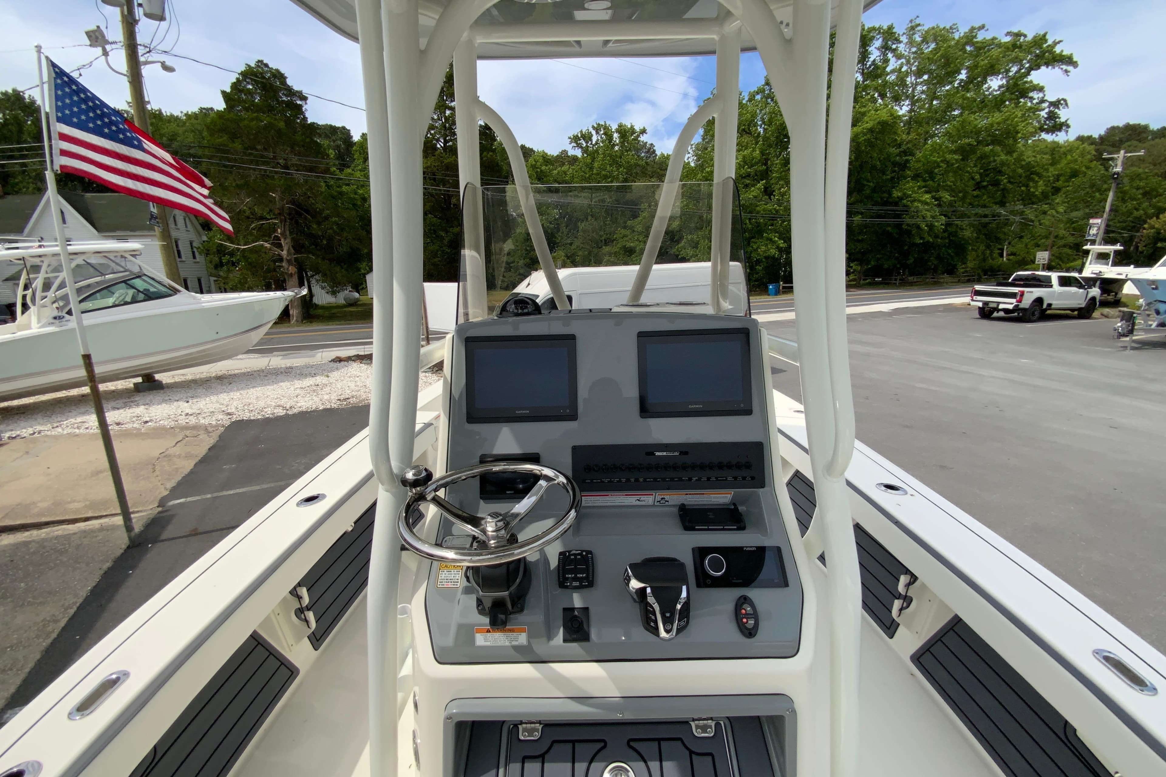 2026 Pathfinder 2600 TRS boat console with dual screens and steering wheel, docked near American flag.