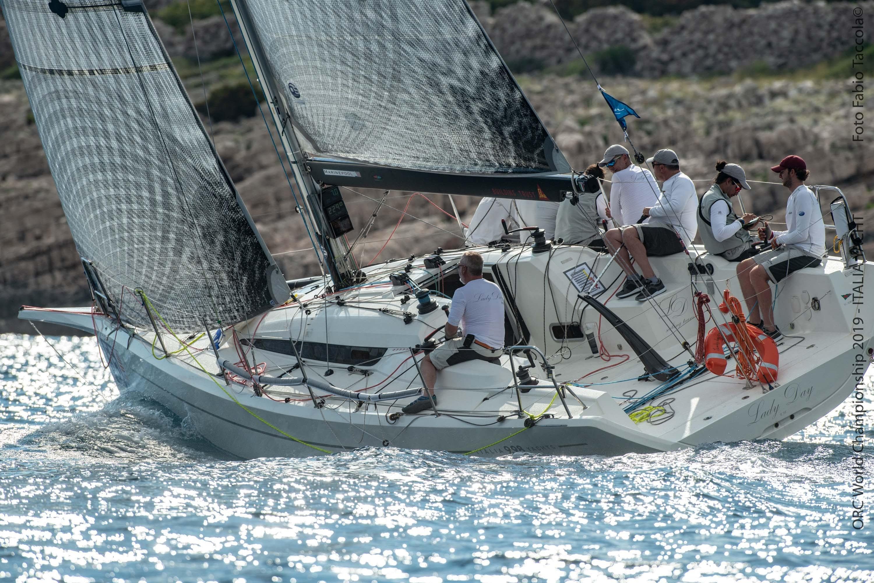 Italia Yachts 9.98 sailing with crew, 2026 model, on sparkling blue water.