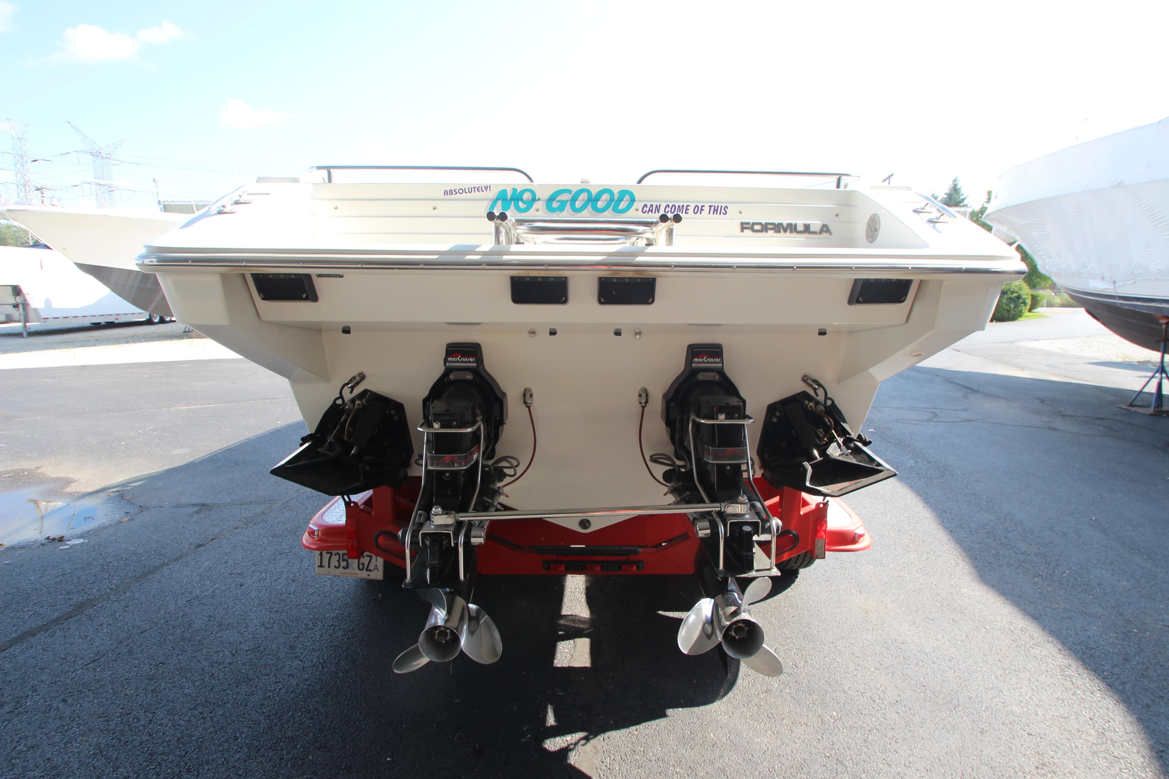 1995 Formula SR1 303 boat with dual outboard motors, parked on a sunny day.