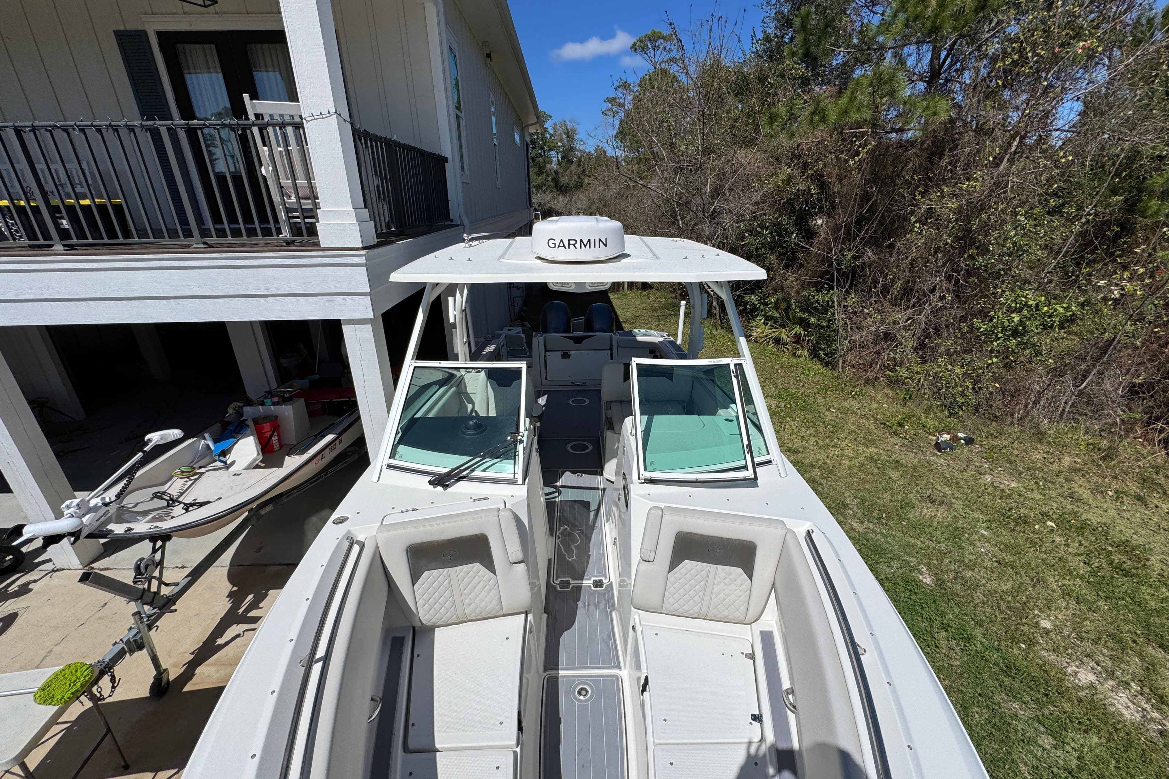 2022 Sailfish 276 DC boat with Garmin equipment, parked near a house and trees.