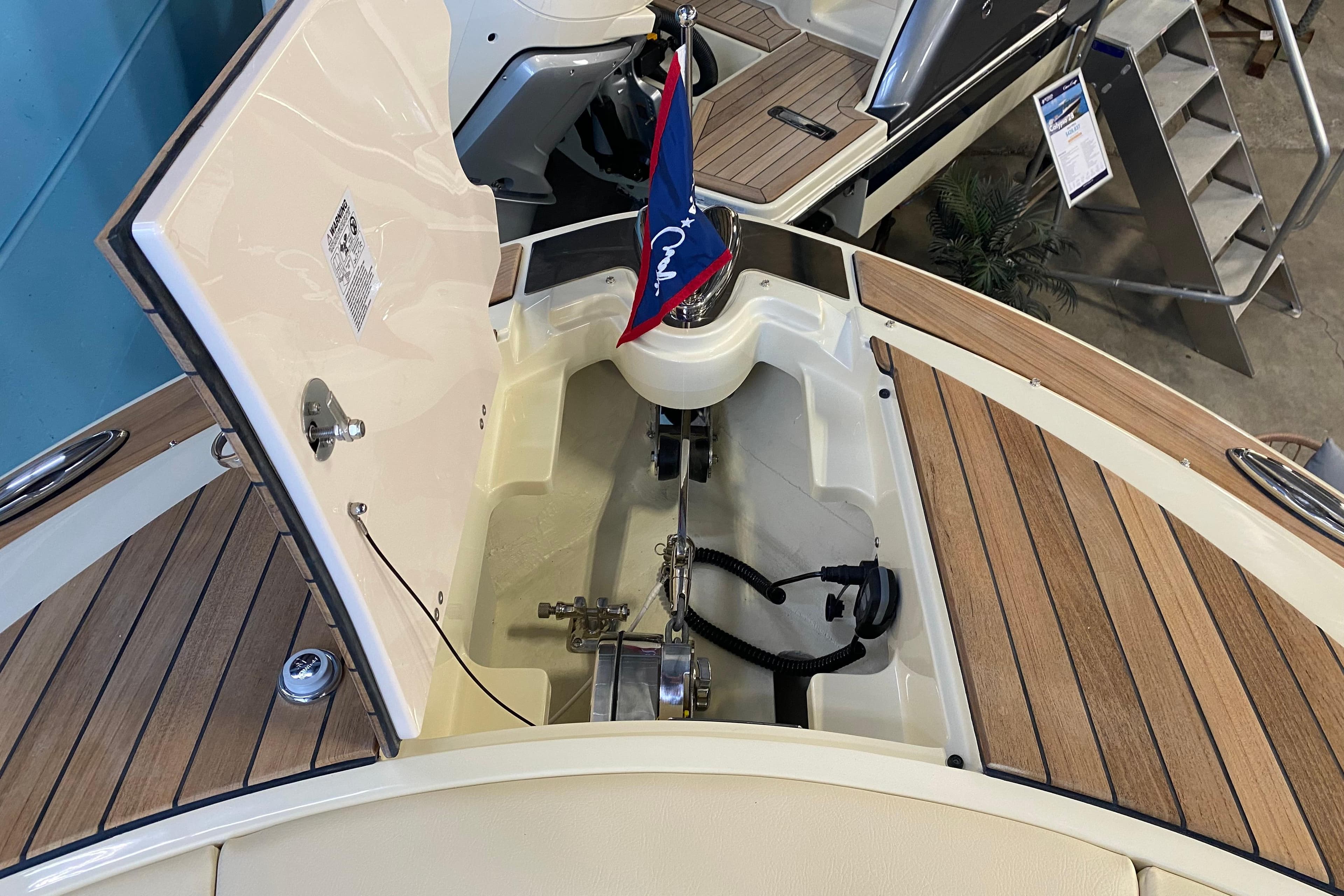 2026 Chris-Craft Launch 31 GT boat anchor compartment with wooden deck and flag.