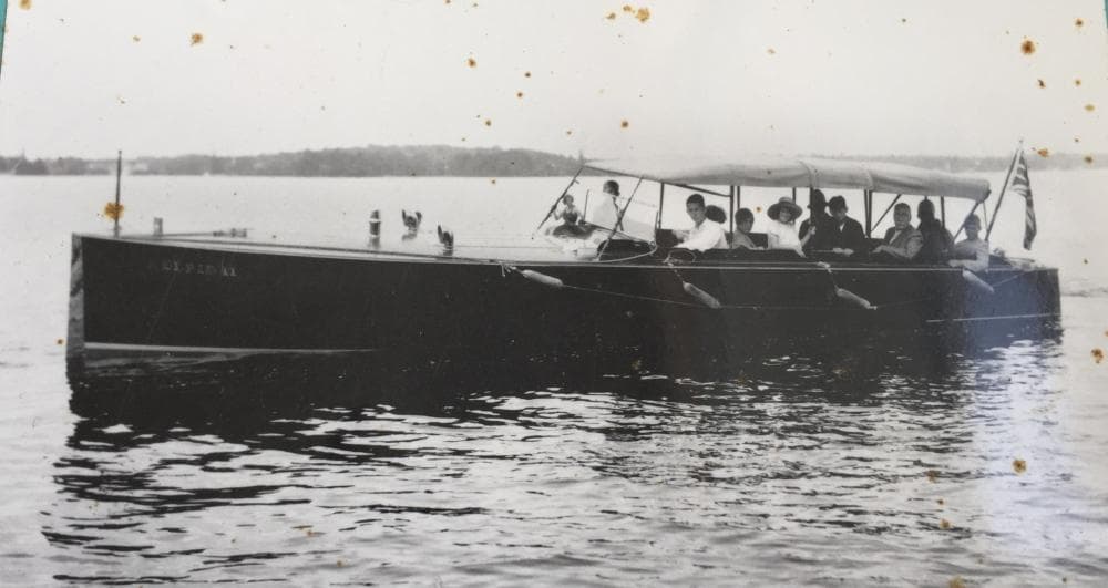 1924 Morris 30 Commuter Launch on calm water with passengers under canopy.