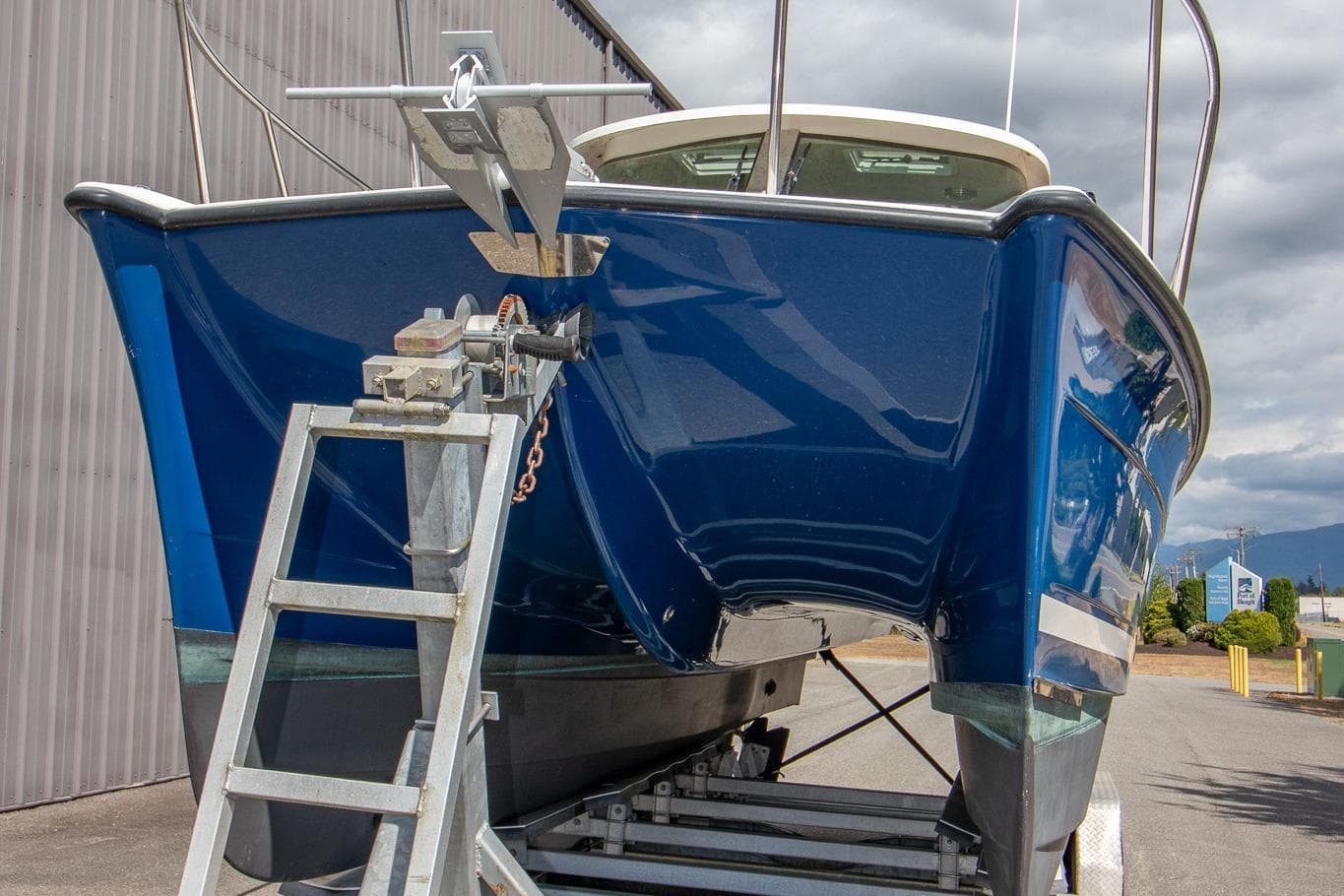 Blue 2013 Aspen C90 boat on trailer, parked outdoors near a building.