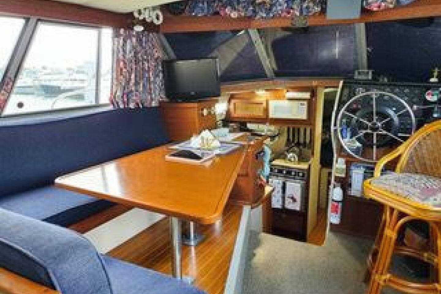 1986 Bayliner 3270 Motoryacht interior with dining area, helm, and kitchen amenities.