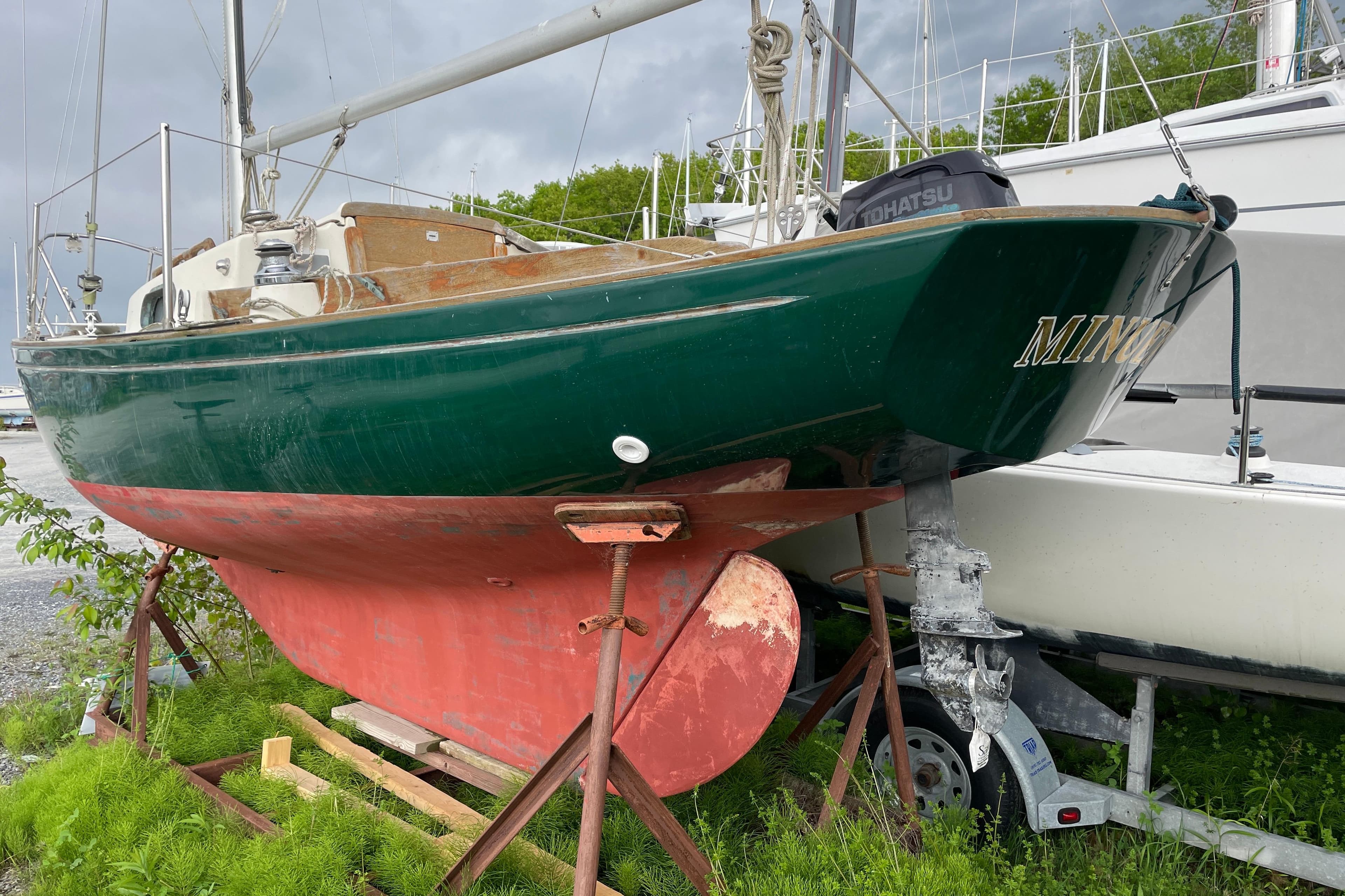 1981 Sea Sprite 23 sailboat on land, green hull, red keel, overcast sky.