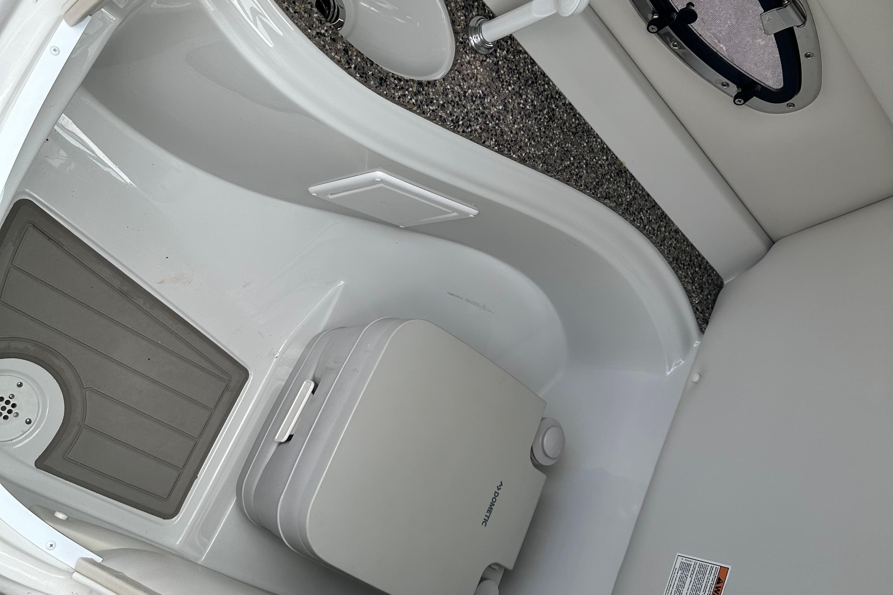 2021 Crownline Eclipse E235 SURF boat interior with compact toilet and flooring.