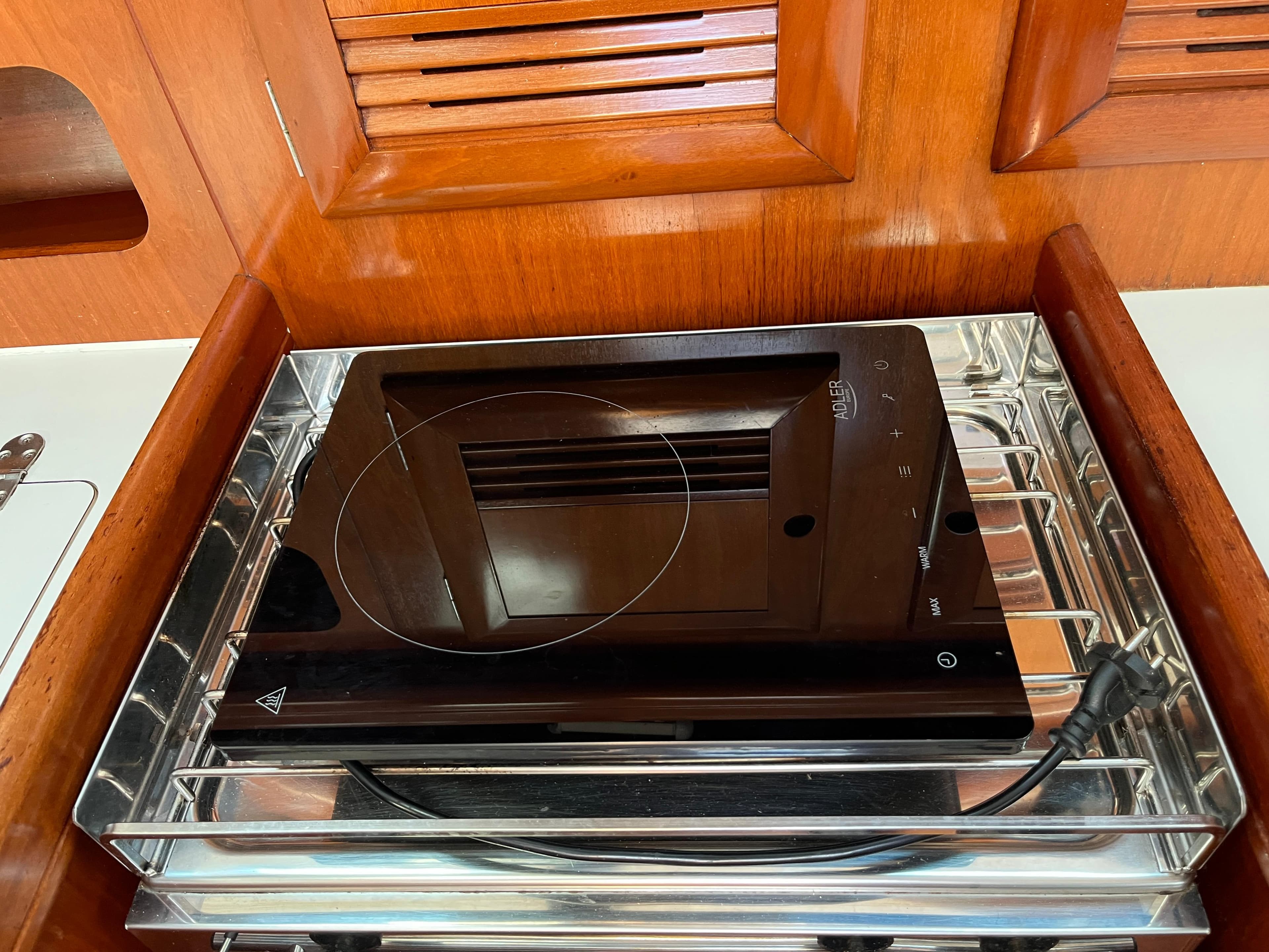 Induction cooktop in Beneteau Oceanis 393 yacht kitchen, 2001 model, with wooden cabinetry.