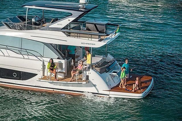 Luxurious Schaefer 600 yacht cruising with passengers, 2026 model, on clear blue waters.