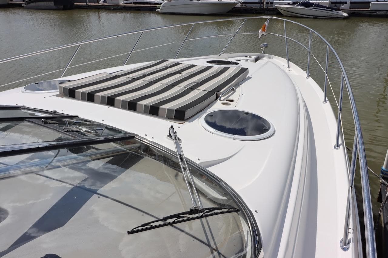 2006 Regal Commodore 4460 yacht with striped sun pad, docked in marina.