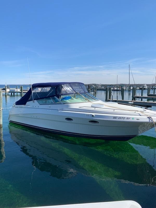 1997 Cruisers Yachts 3120 Aria docked, blue canopy, calm waters.