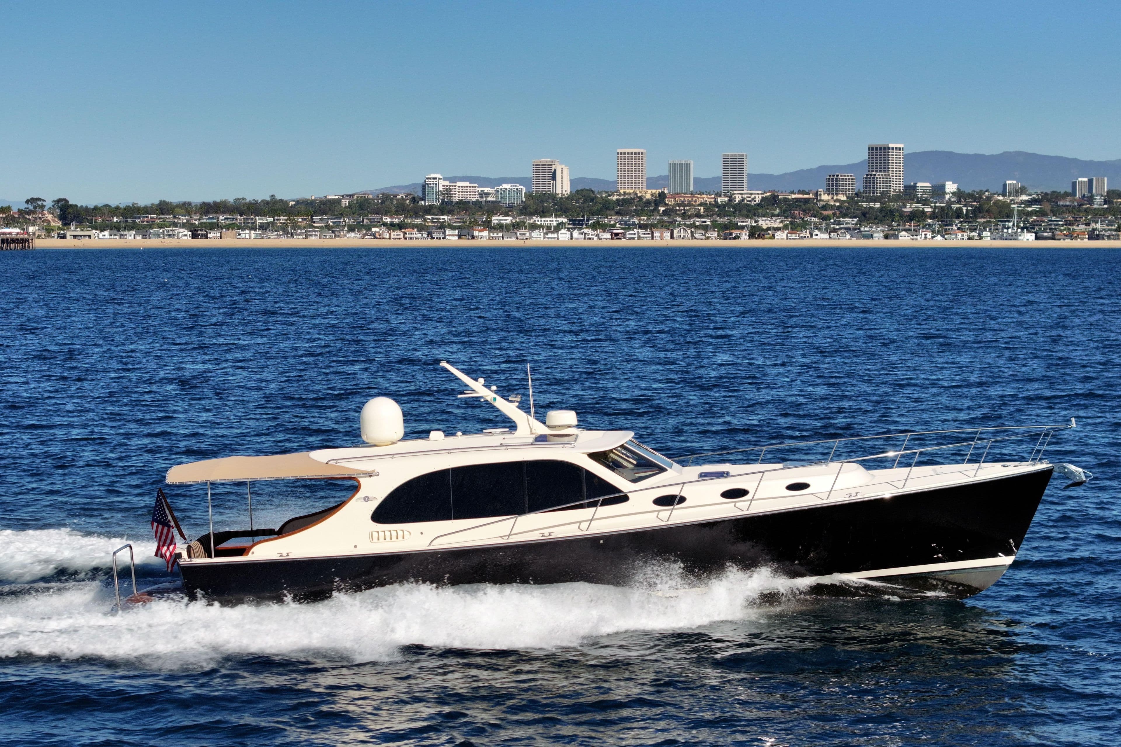 2015 Palm Beach Motor Yachts PB45 cruising on blue ocean with city skyline backdrop.