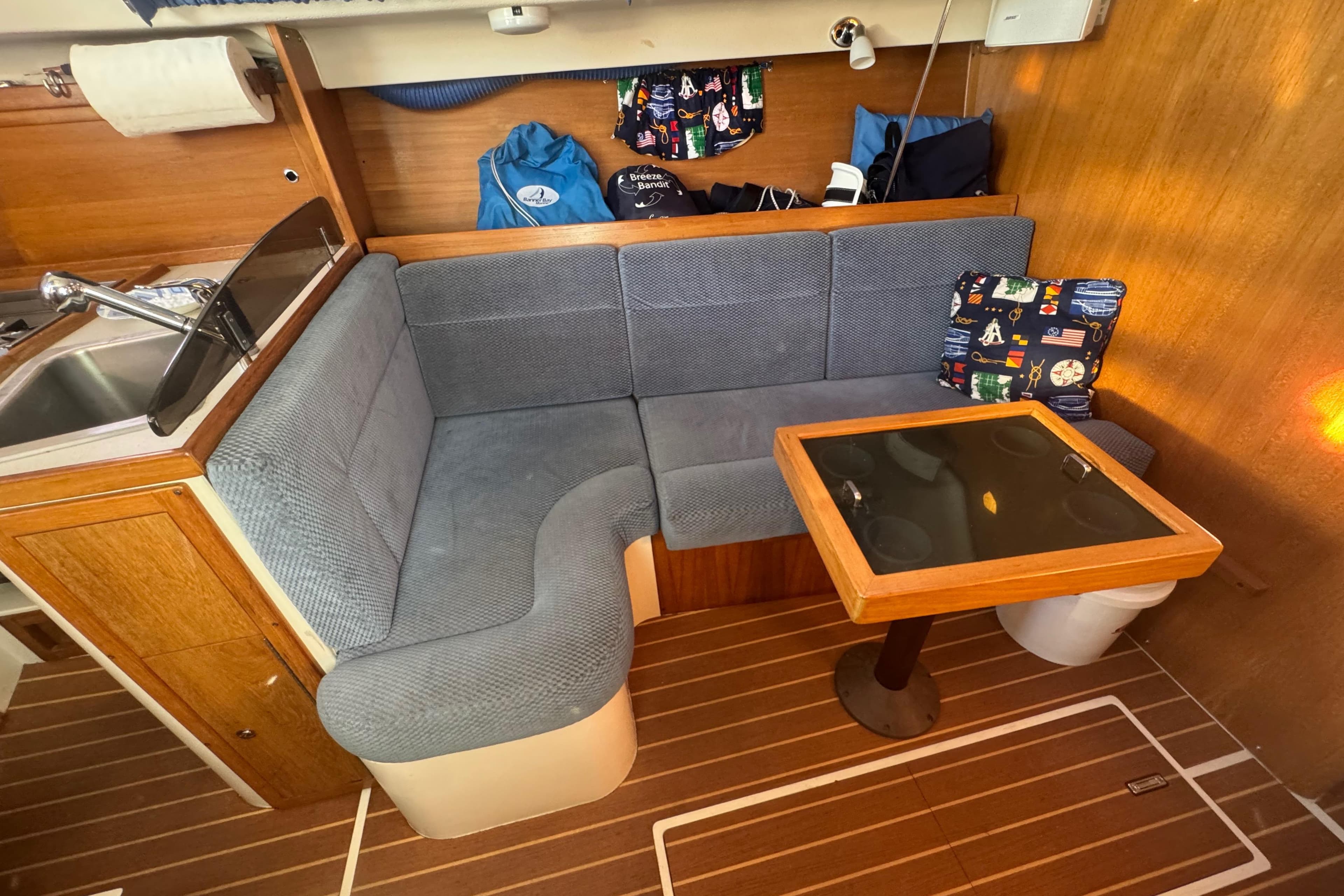 Cozy interior of 2006 Catalina 309 sailboat with cushioned seating and wooden table.