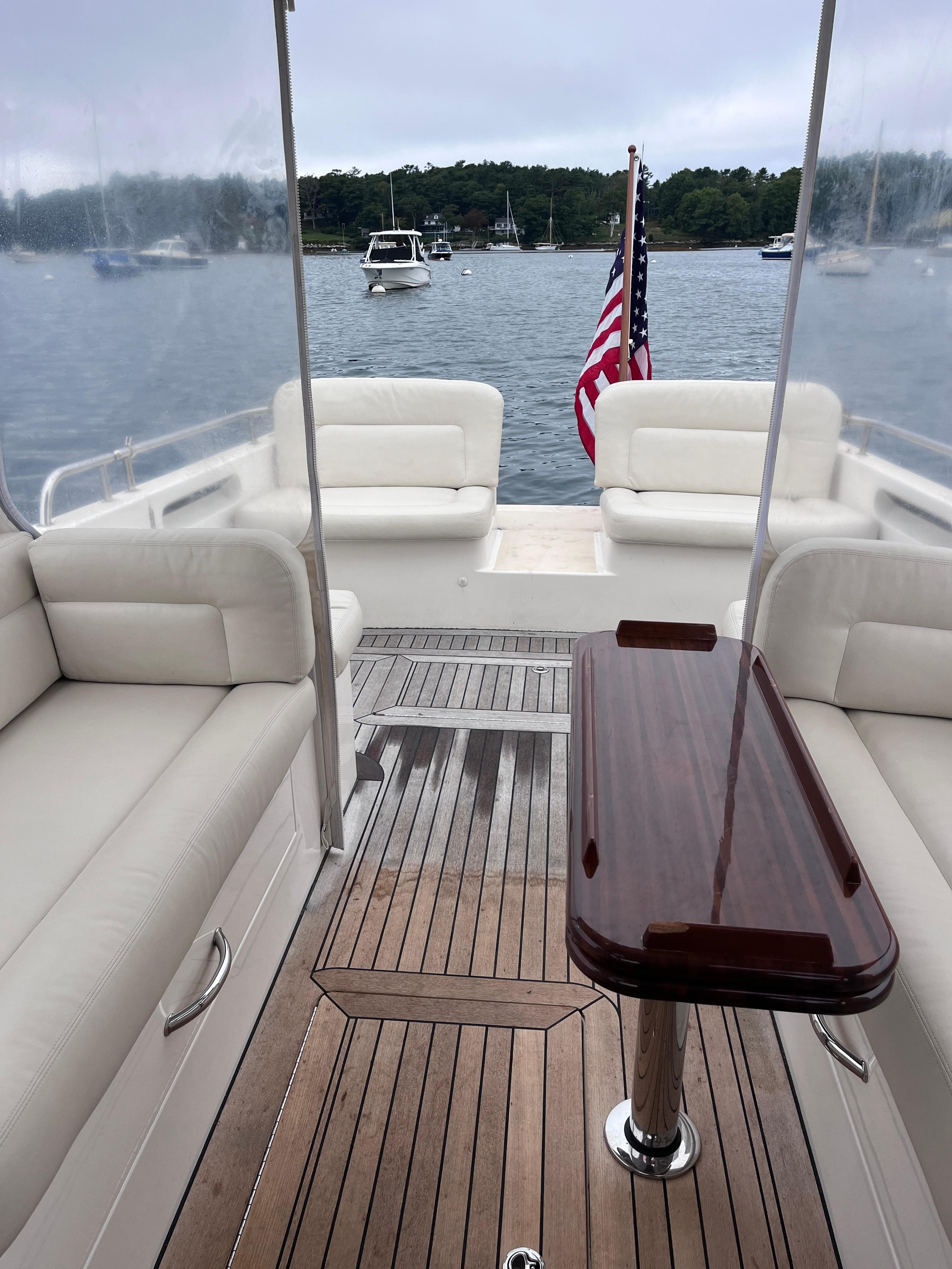 2014 MJM 36z Downeast boat interior with seating and wooden table, docked on a calm lake.