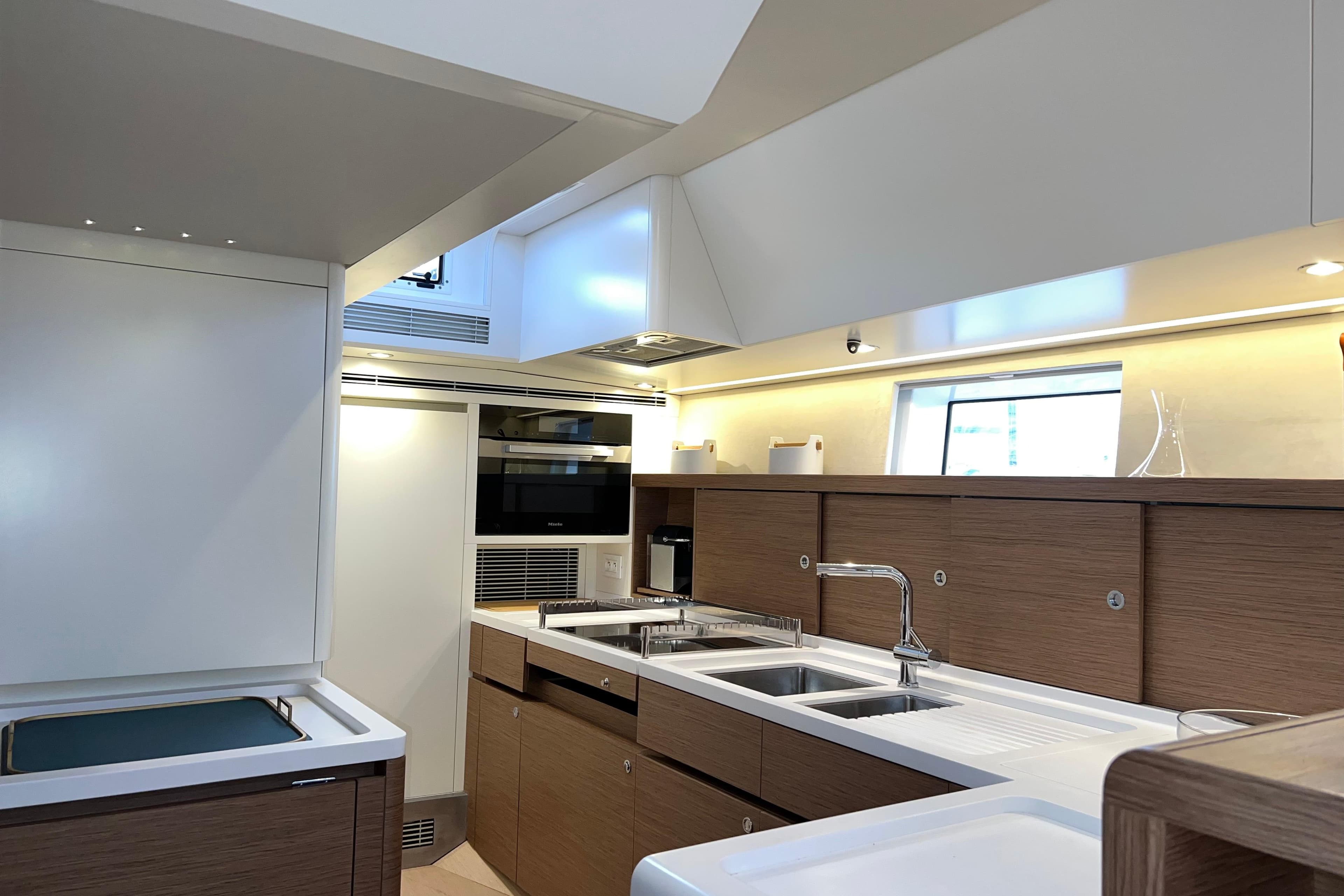 Modern kitchen interior on a 2021 CNB 66 yacht, featuring sleek cabinetry and appliances.