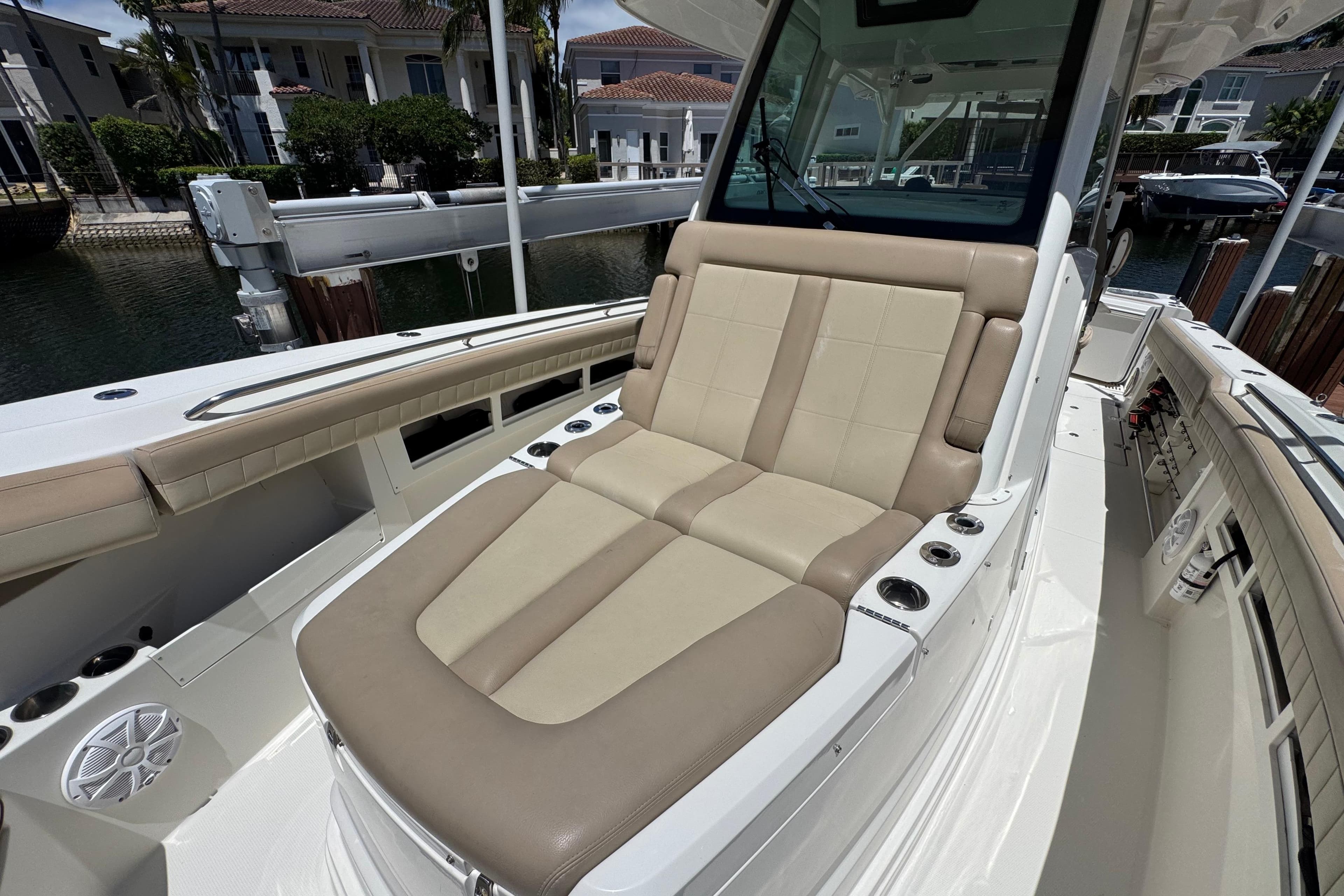2019 Sailfish 360 CC boat with beige seating, docked near waterfront homes.