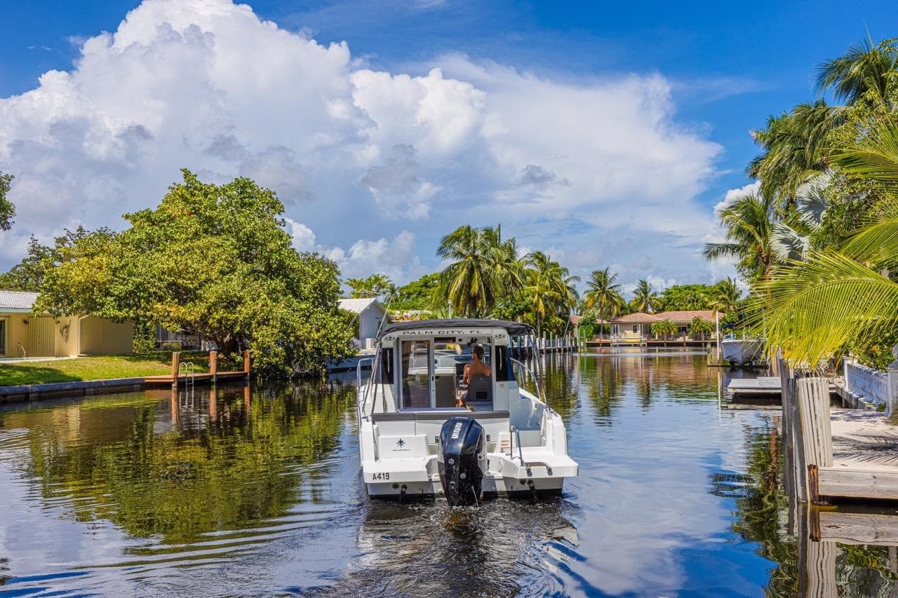 2022 Jeanneau NC 795 Series 2 cruising on a scenic, tropical canal.