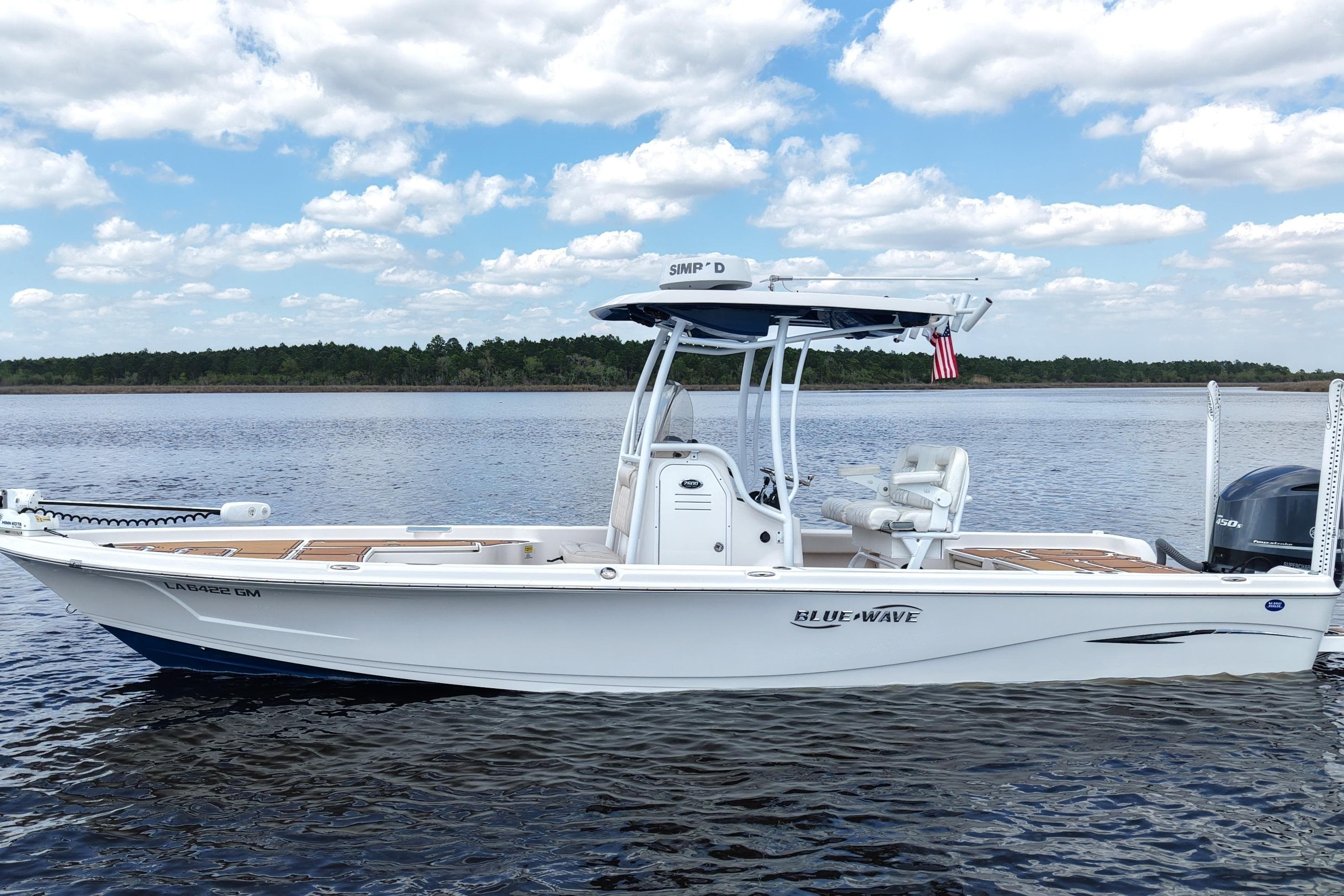 2021 Blue Wave 2600 PureBay boat on calm water under a partly cloudy sky.