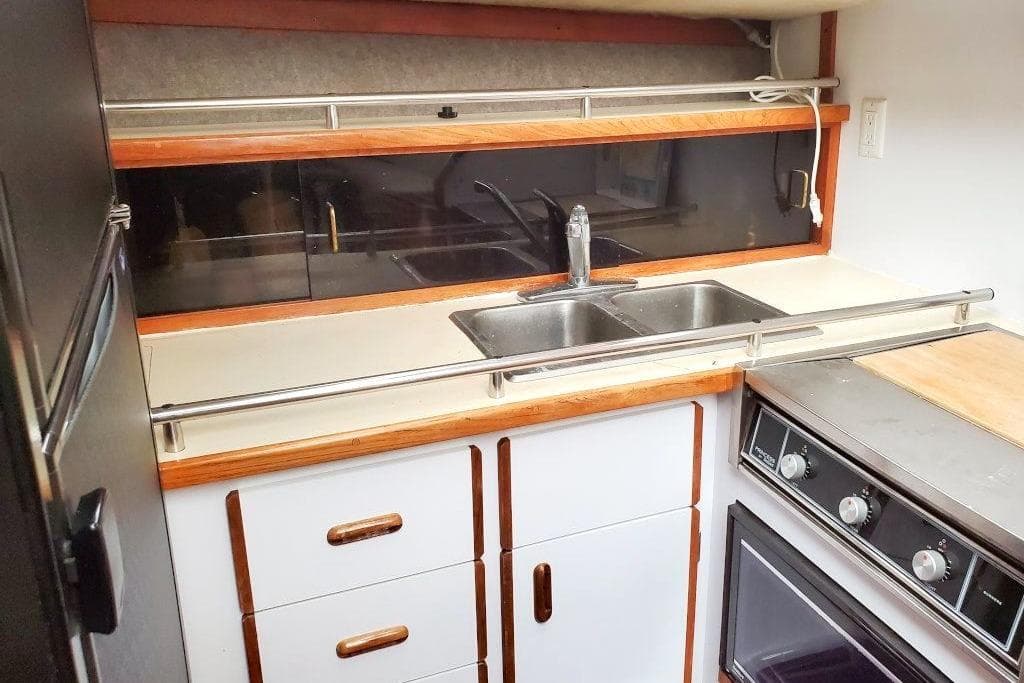 1986 Carver 3607 Aft Cabin Motor Yacht kitchen with sink, stove, and cabinetry.