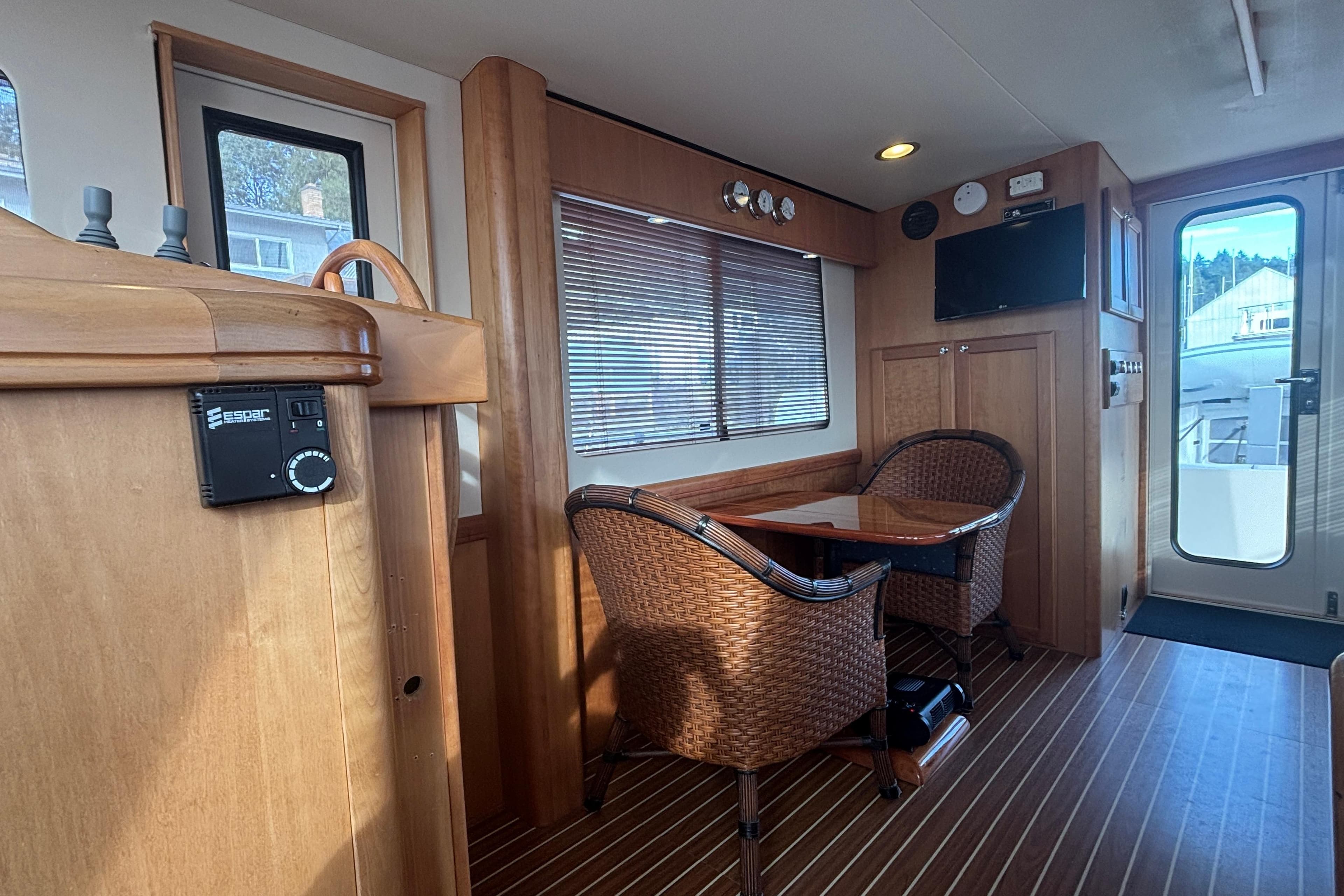 Interior of 2007 Mainship 34 Trawler with wood paneling and wicker chairs.