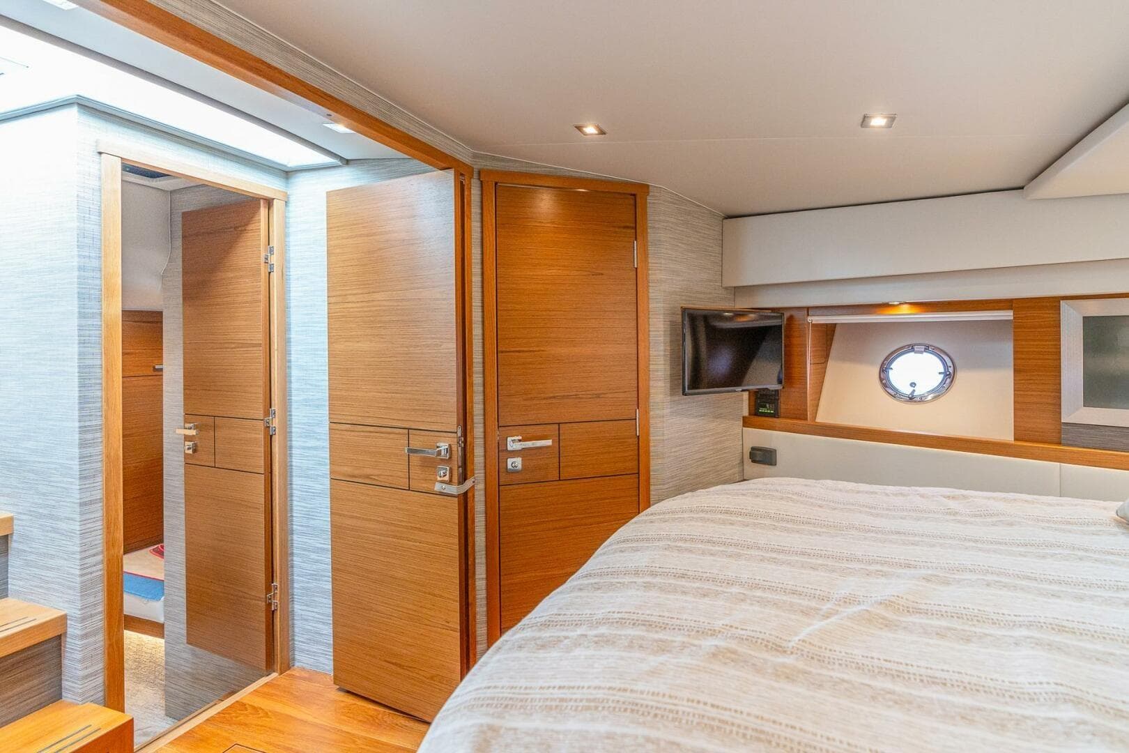 Luxurious 2021 Tiara Yachts F44 Flybridge cabin interior with wood accents and porthole window.
