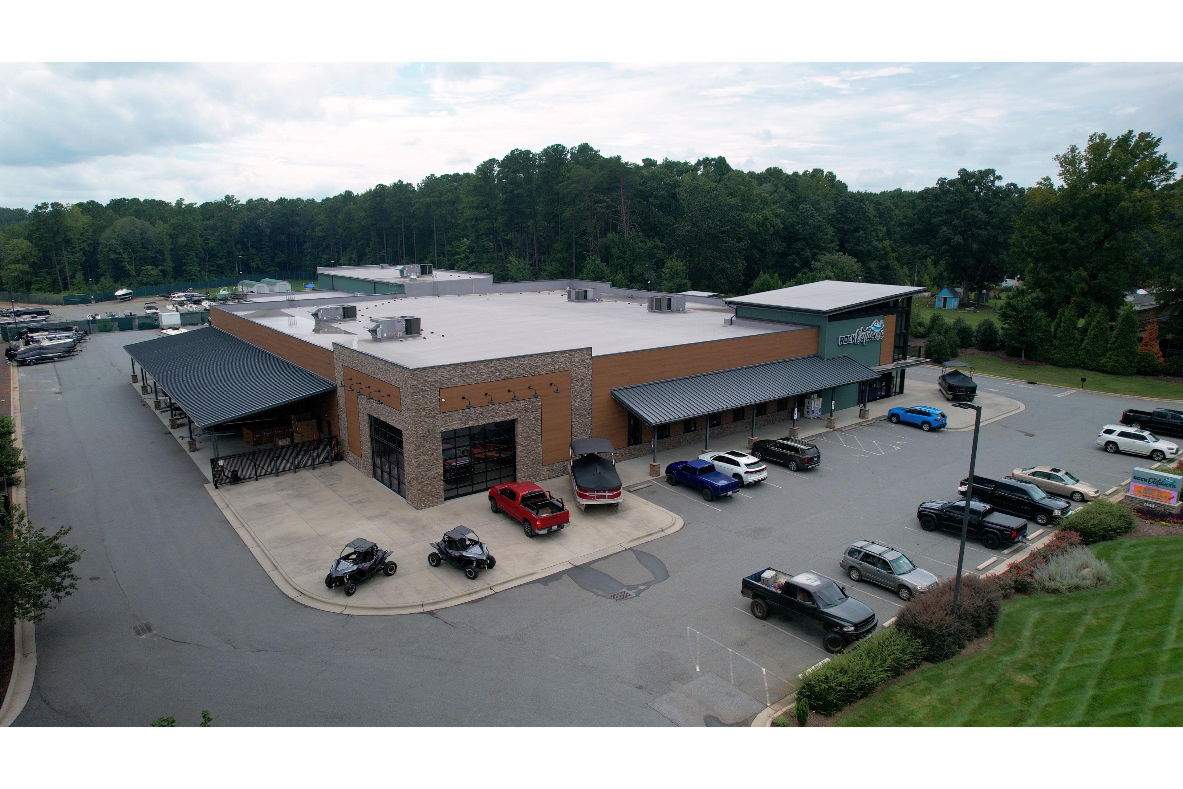 Aerial view of a commercial building with parking lot and surrounding greenery.