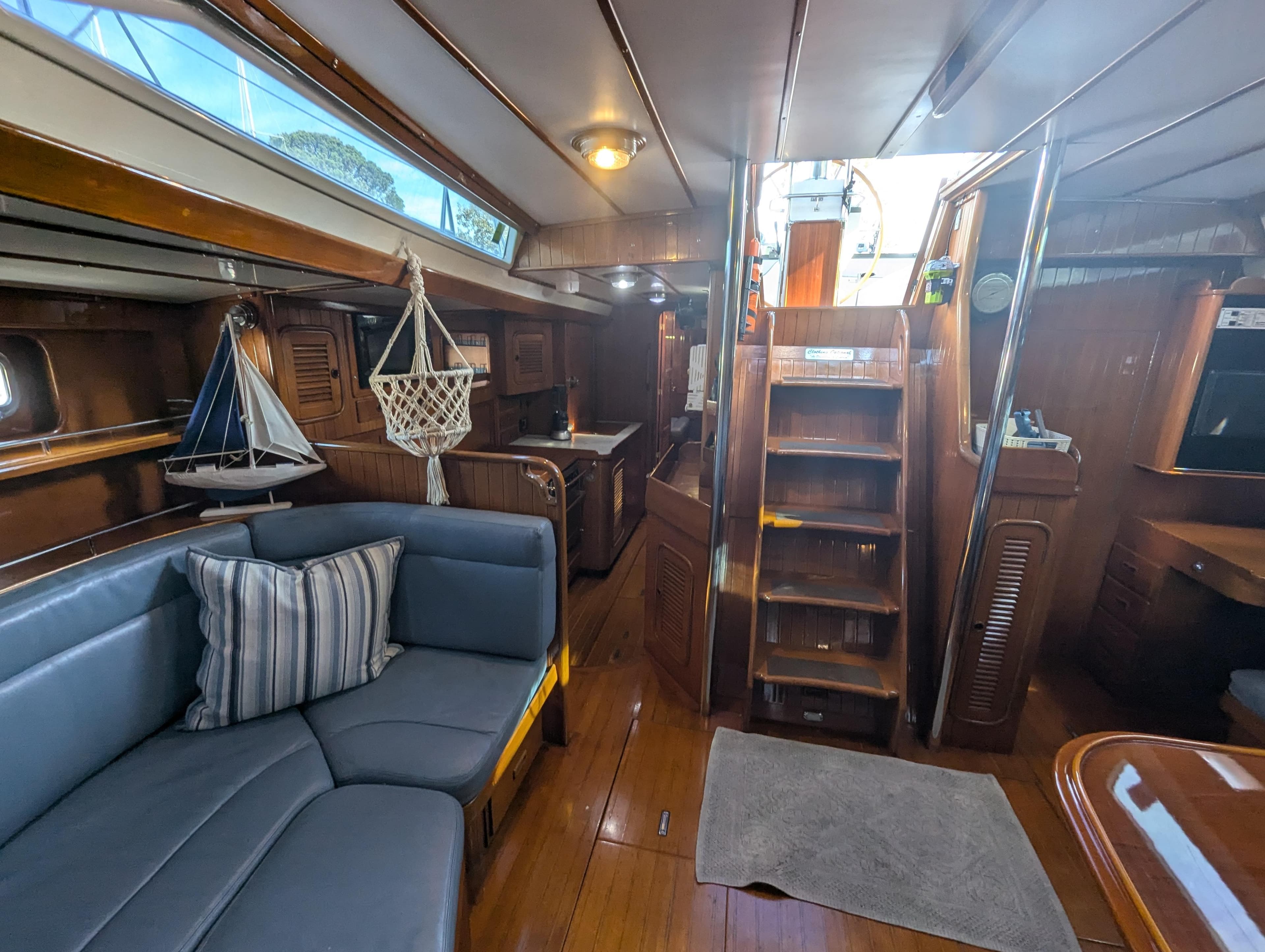 Interior of 1989 Tayana 55 yacht with wooden finishes and cozy seating area.
