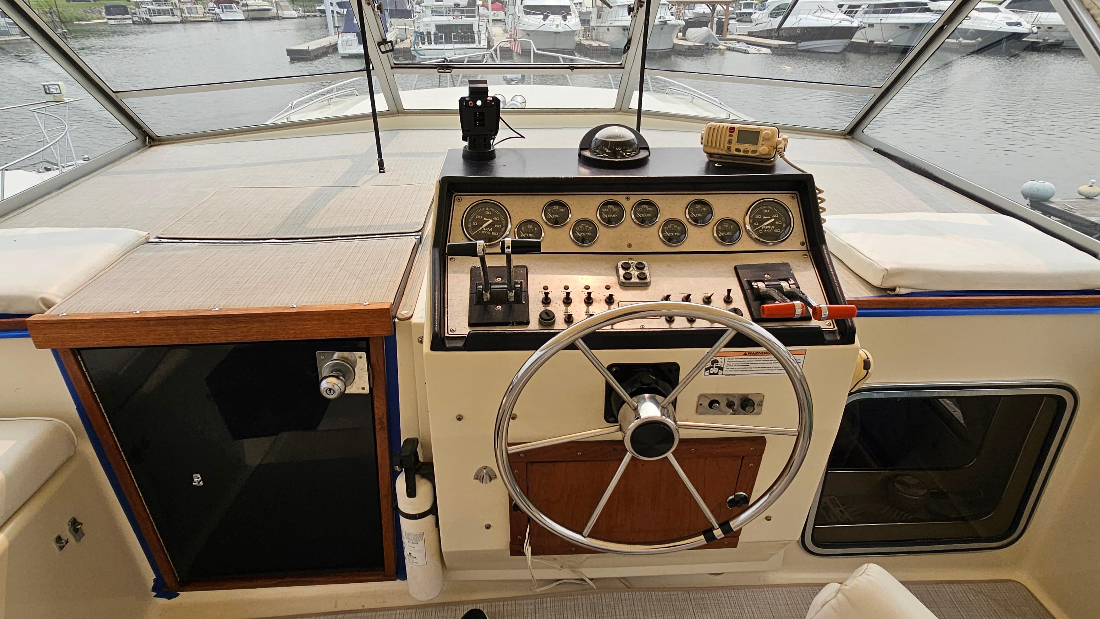 1986 Chris-Craft 381 Catalina helm with steering wheel and control panel, docked at marina.