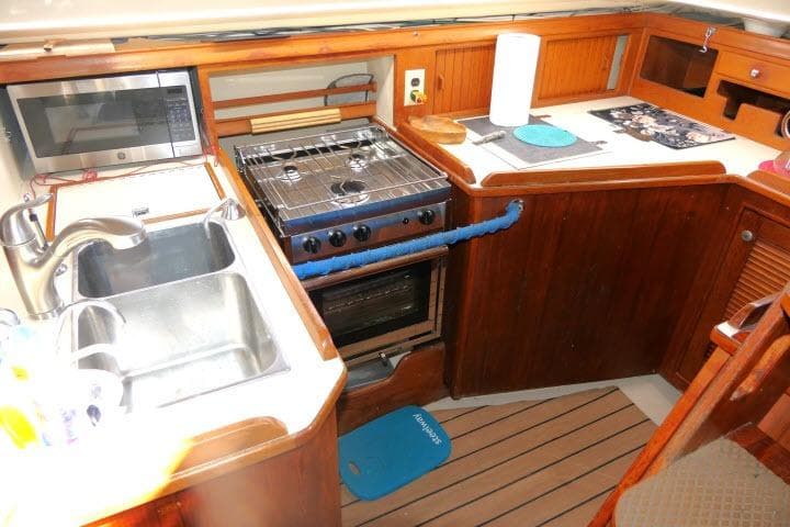 Galley kitchen in 1999 Island Packet 45 sailboat with stove, sink, and microwave.