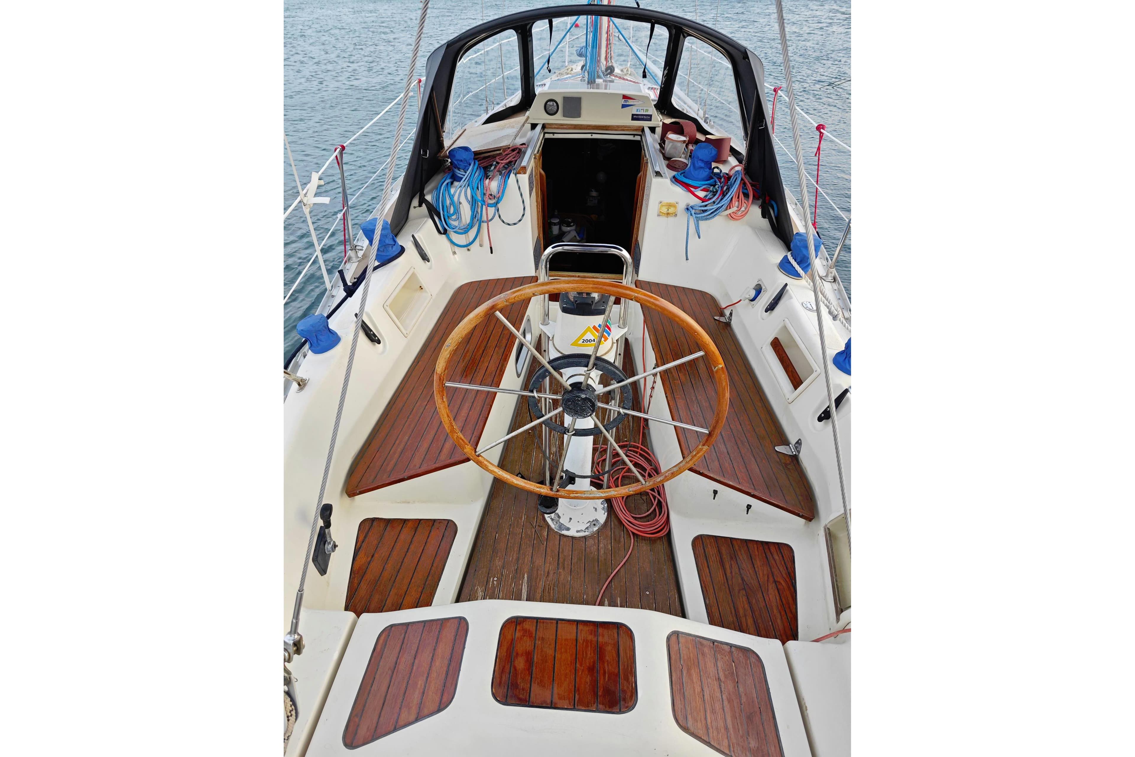 Cockpit of 1985 Bavaria BAVARIA 960 sailboat with wooden deck and steering wheel.