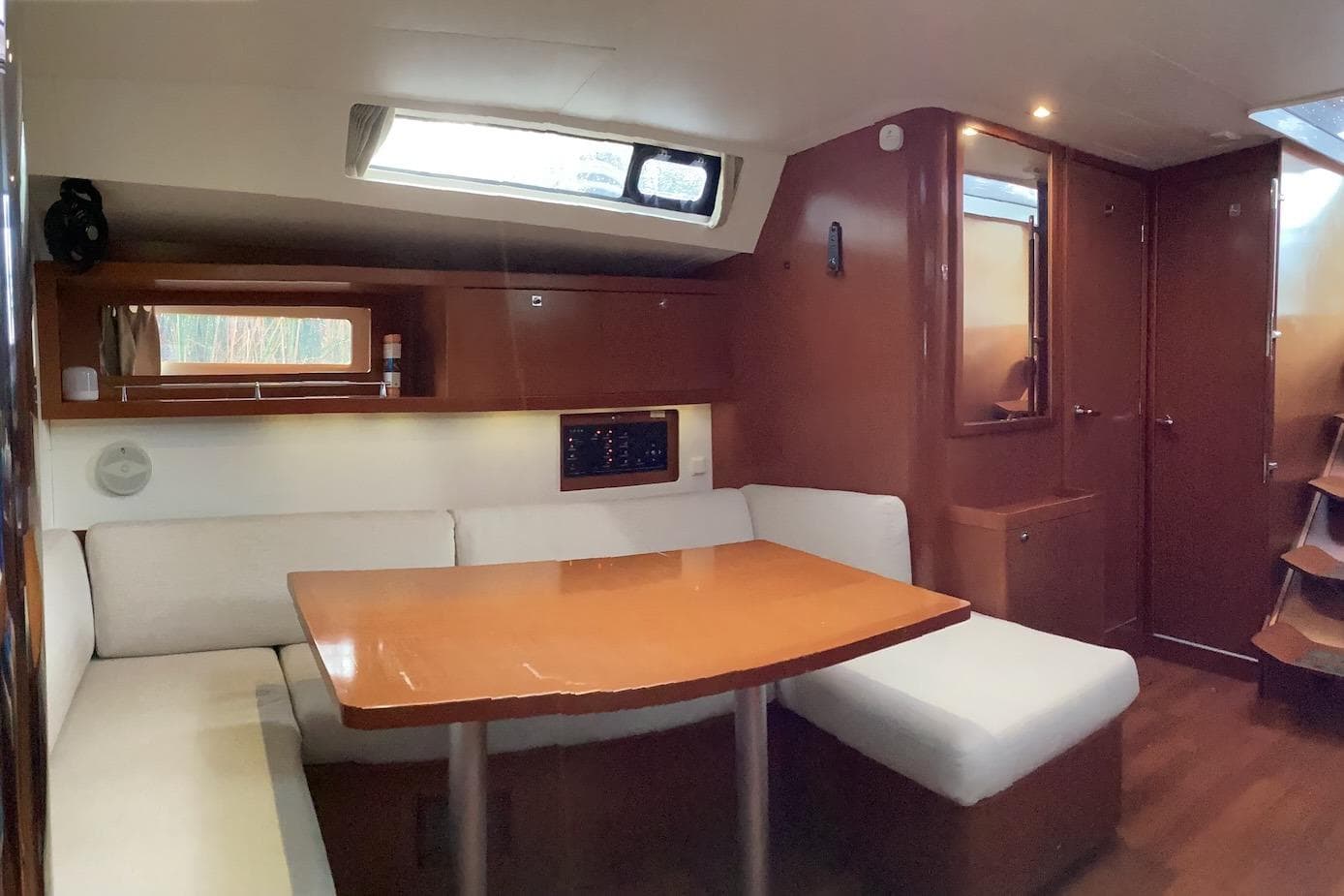 Interior of 2012 Beneteau Oceanis 45 yacht with cozy seating and wooden table.