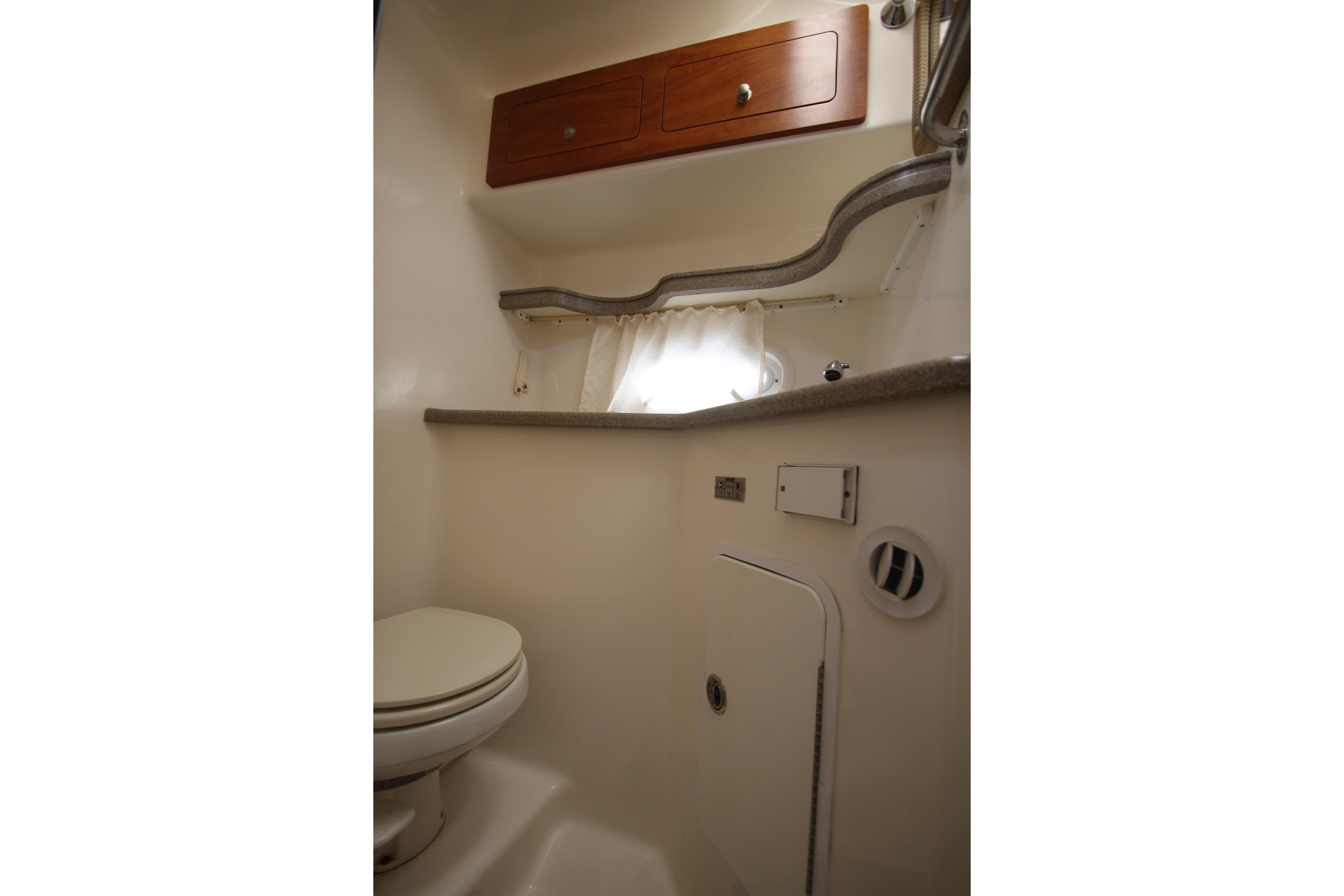 2008 Rinker 330 Express Cruiser bathroom with toilet, storage cabinets, and compact design.